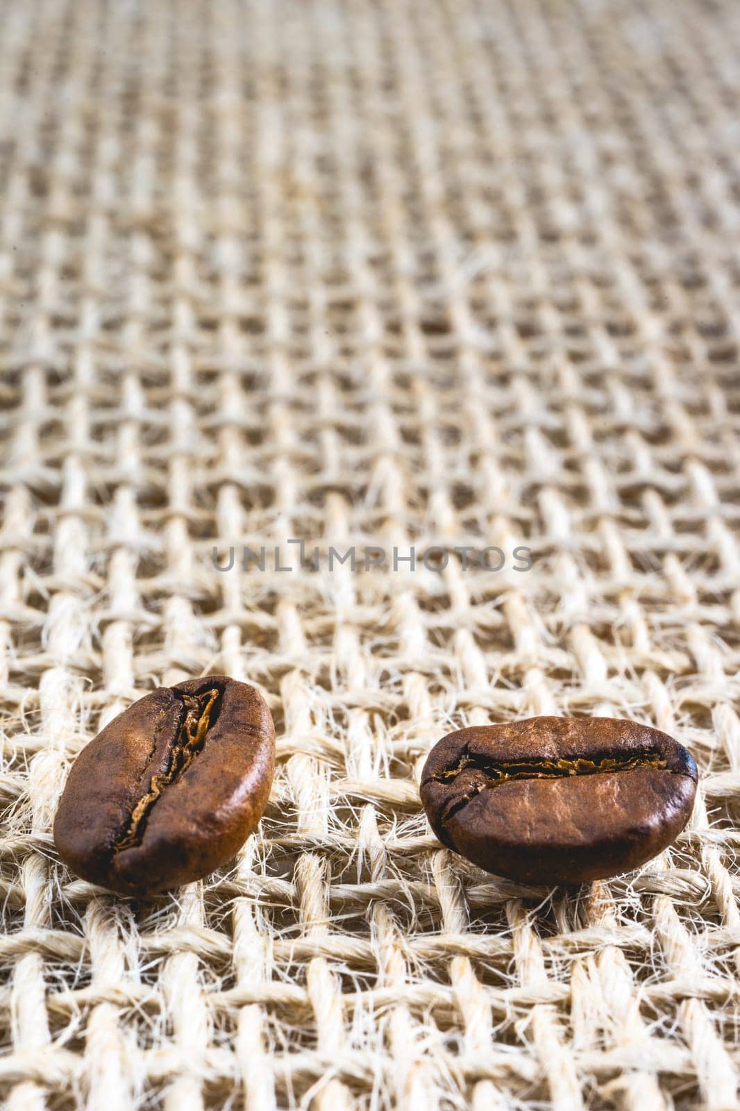 Close up from a few coffee beans laying down on a Burlap fabric background. Background voor coffee related products.