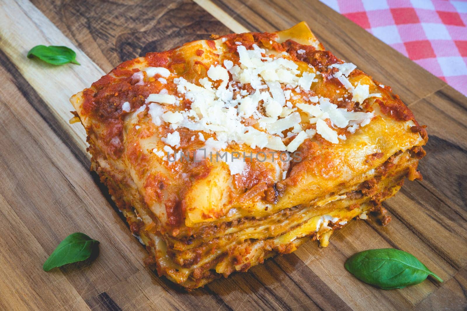 Top view from a homemade Lasagna, on a wooden cutboard, decorated with basil.