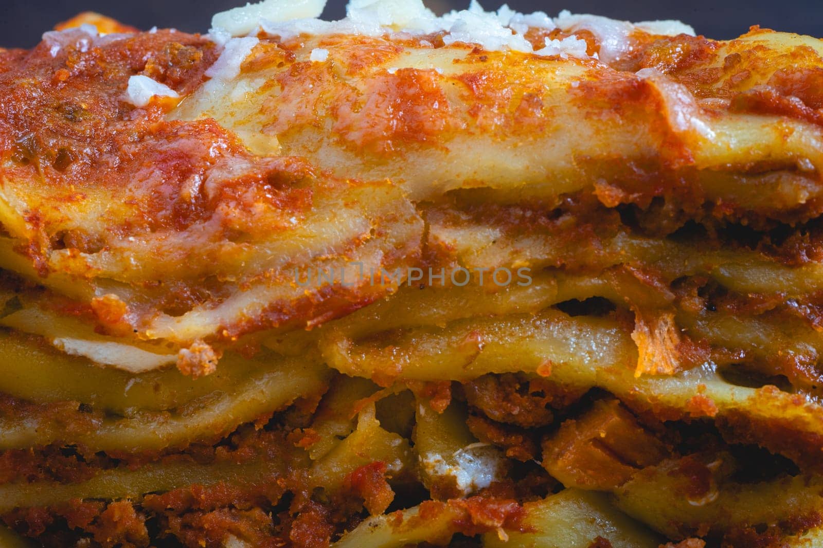 Close up view from a home made Lasagna, on a wooden table, and a dark background.