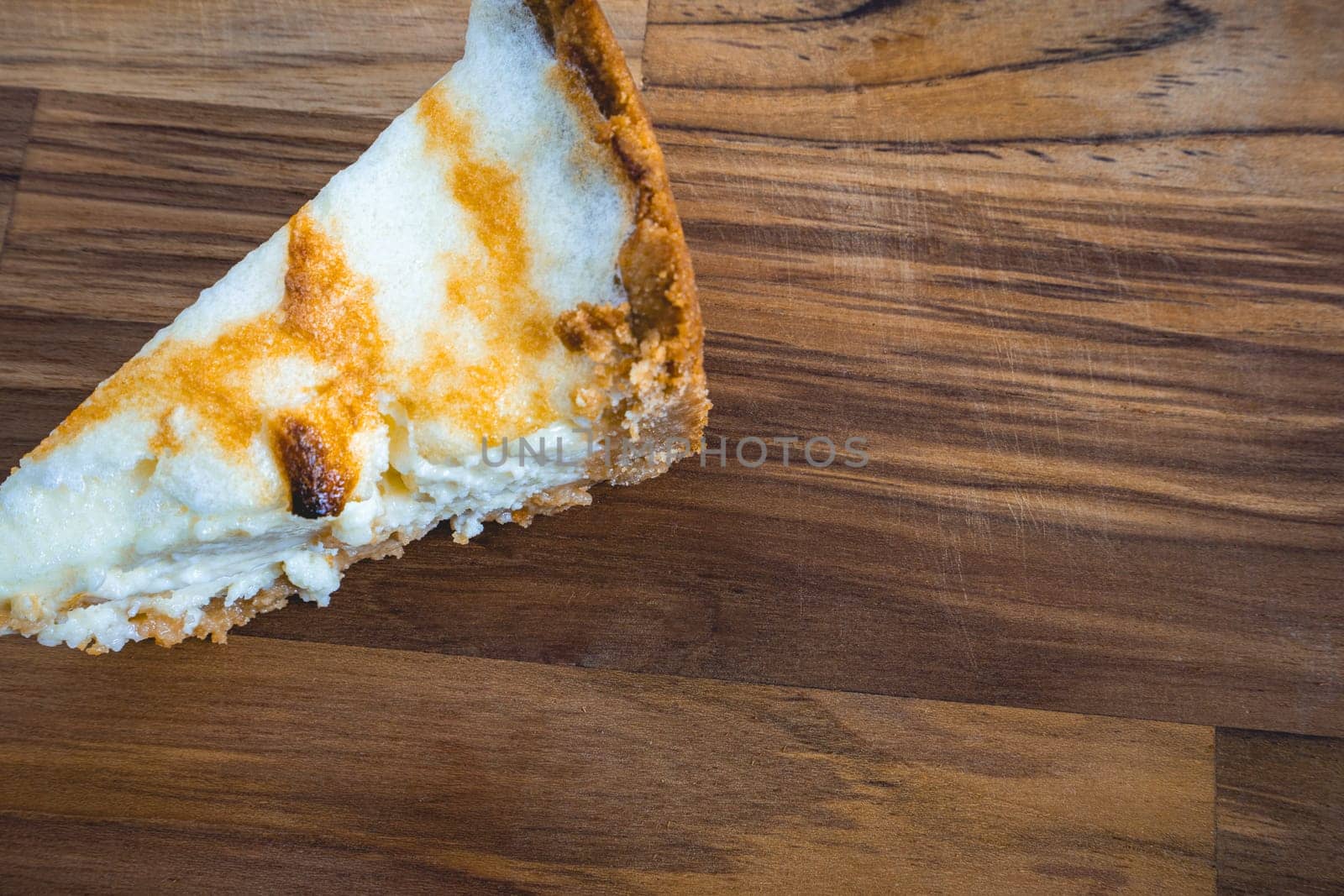 A slice of a fresh home made lemon pie, on a wooden background.