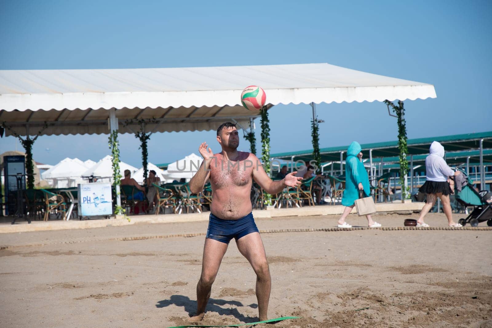 young guy in black shorts serves the ball while playing beach volleyball on the sea during vacation, ball matches and active activities, Green Max Hotel,Belek, Turkey, May 31, 2024