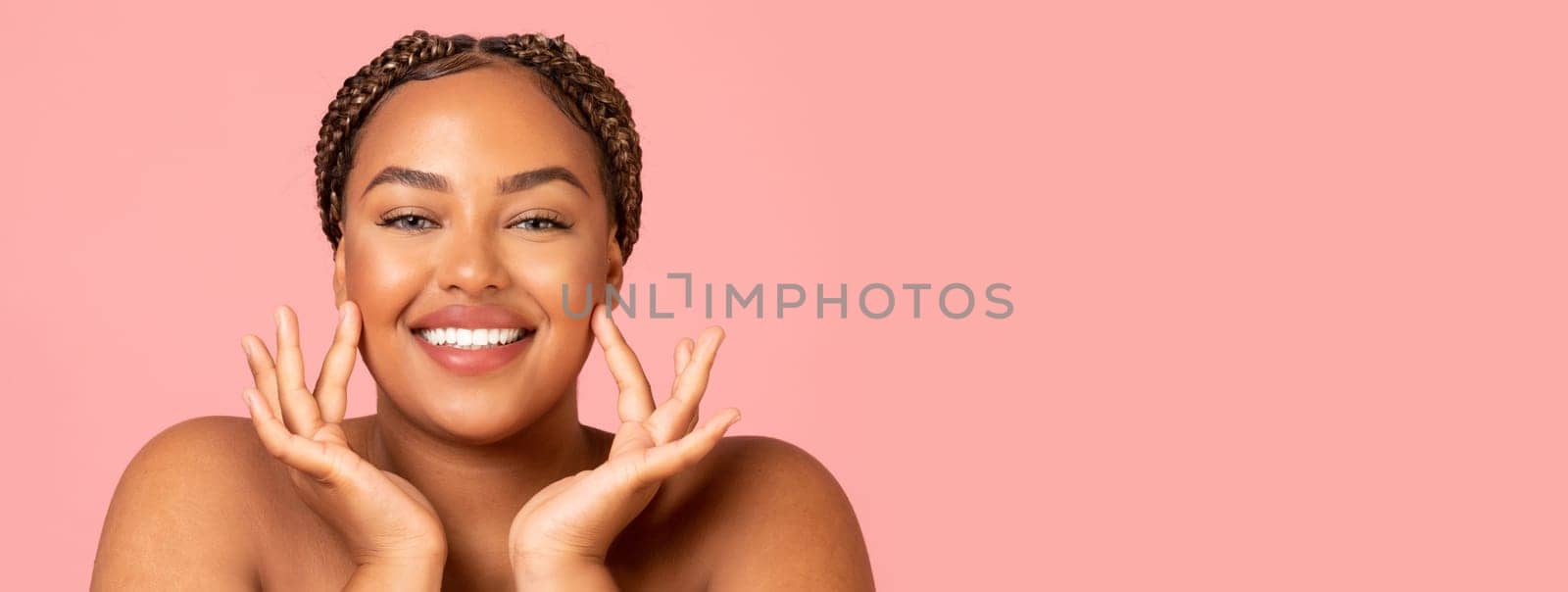 Facial Skincare. Attractive Black Woman Touching Face Moisturizing Smooth Skin Posing Smiling To Camera Over Pink Background In Studio. Beauty Routine And Pampering Concept, Copy Space
