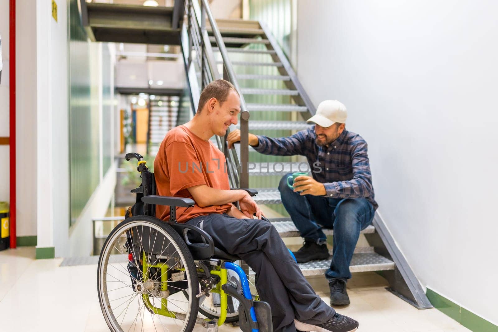 Man with disability talking with colleague in a coworking coffee break into a modern building