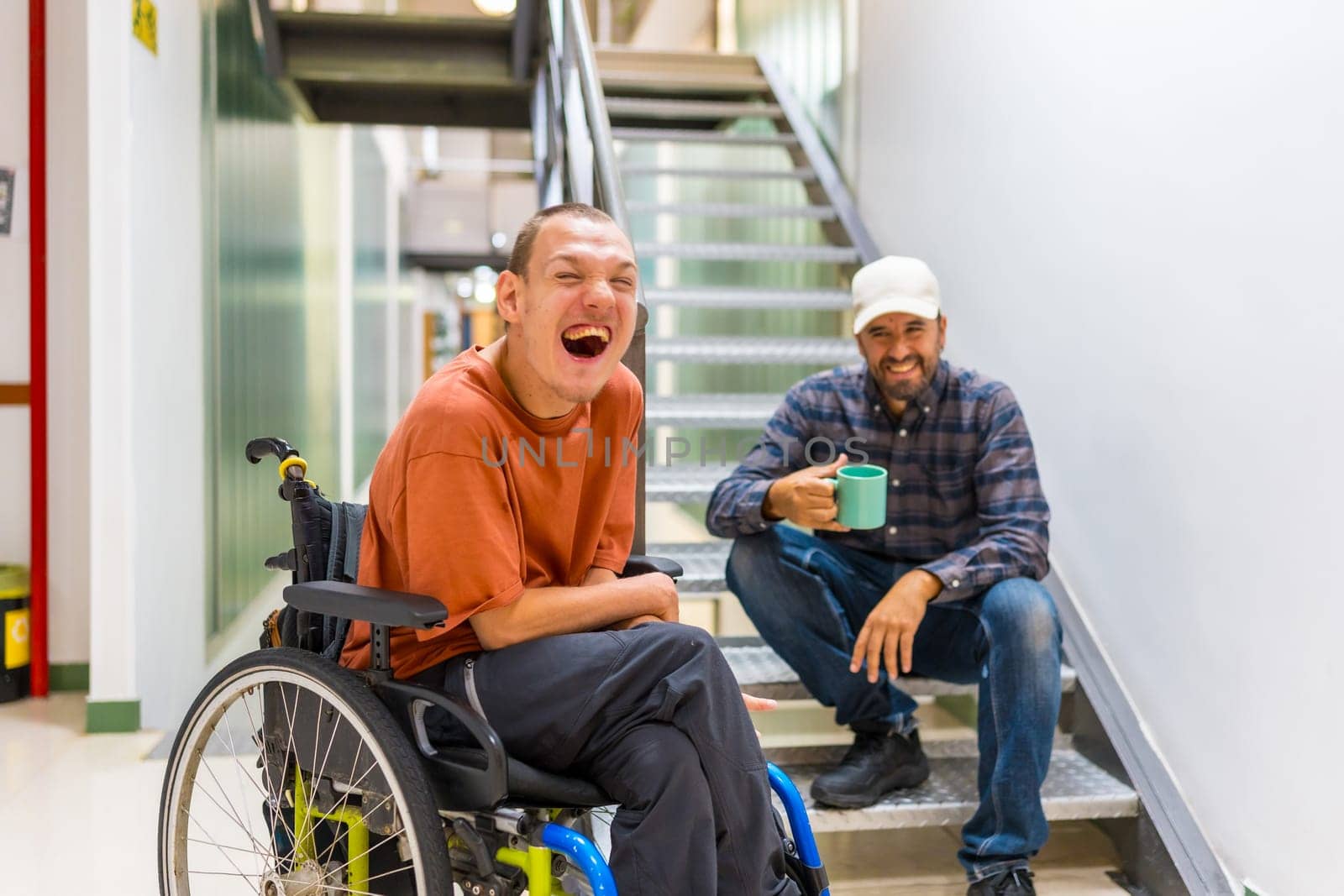 Man with cerebral palsy having fun with teamwork in coworking during a coffee break indoors