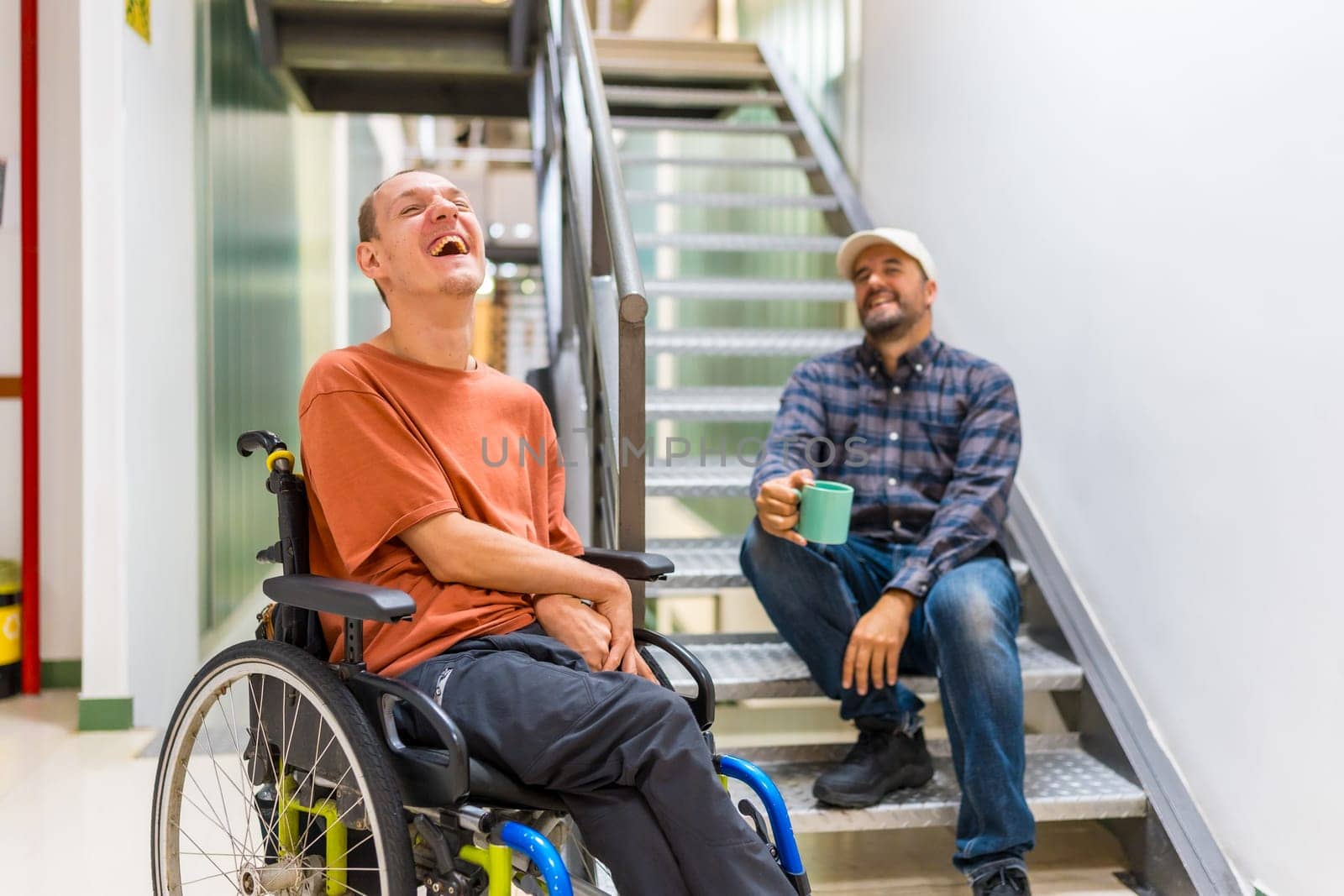 Male caucasian freelance and disabled coworker laughing and talking during coffee break at coworking