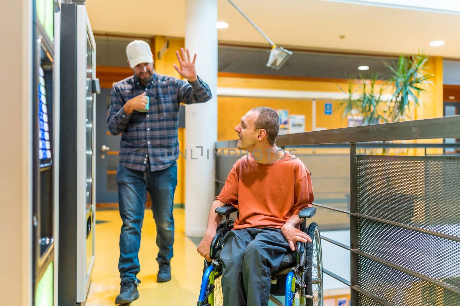 Man with disability and colleague chatting next to vending machine in a modern coworking