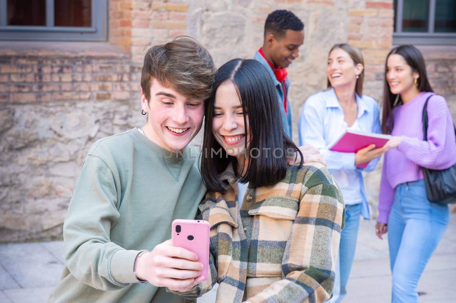 Happy multiracial students using cell phone to chat online. University life concept
