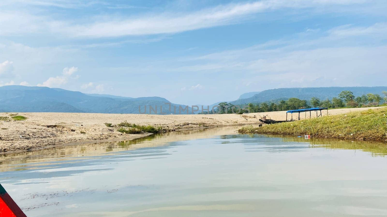 A serene body of water with a blue tent pitched nearby, framed by majestic mountains in the background. Ideal for camping, travel, and nature projects.