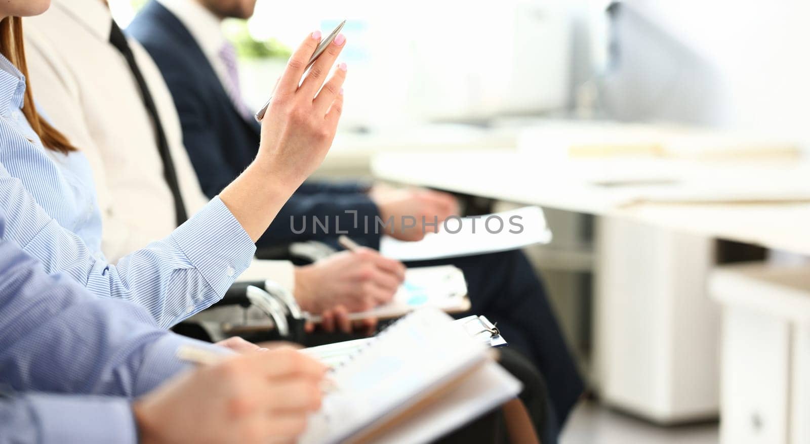 Female hand is raised up with silver pen in hall for an event conference asks to choose job interview concept.