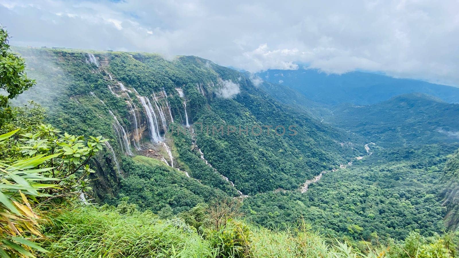 A majestic waterfall cascading down a mountain, surrounded by rugged terrain and lush greenery. Ideal for nature, adventure, and landscape projects.