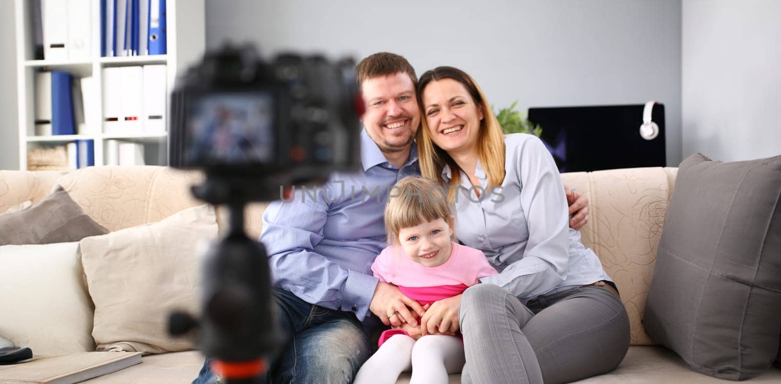 Young happy family sit on couch making photo session portrait looking at camera