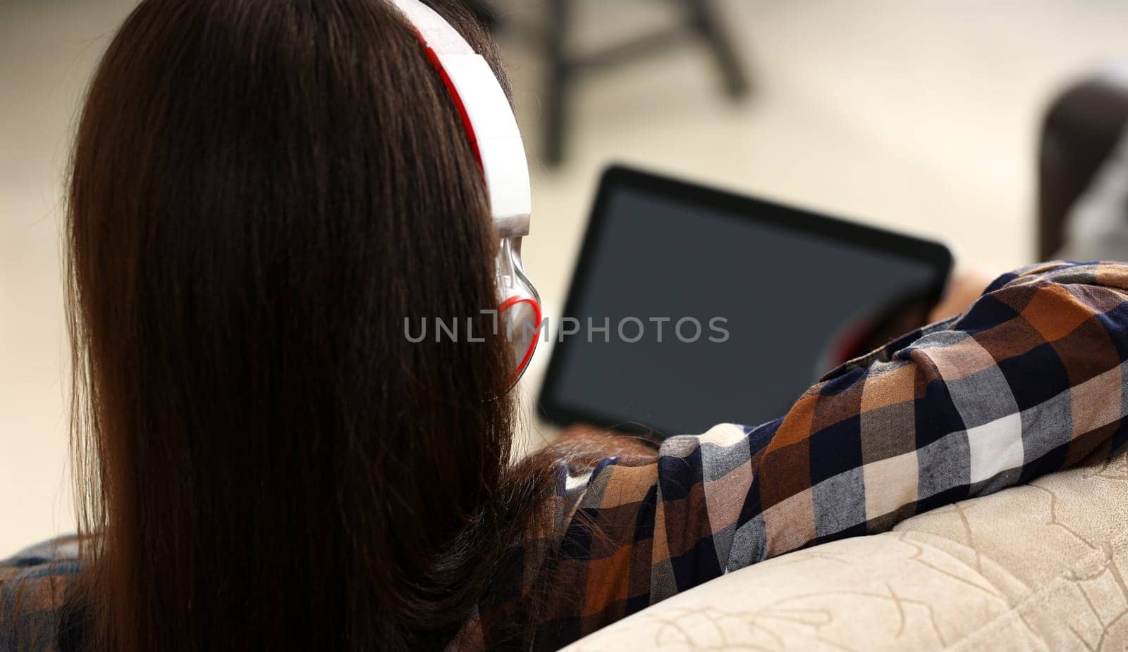 Female hand holds black tablet pad in home setting while sitting on couch engaged an internet surfing using application mail tracking food delivery display leisure listering music concept closeup.