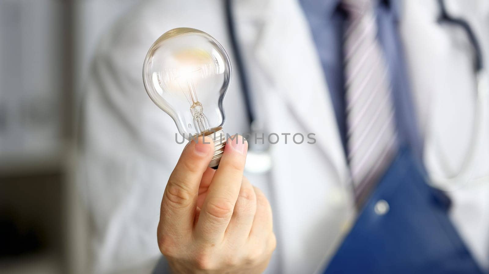 Male doctor hand holding lightbulb as bright idea invention symbol closeup