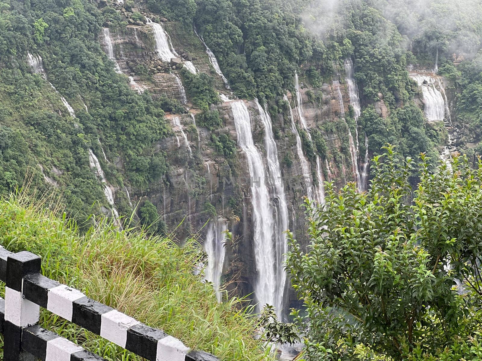 A majestic waterfall cascading down a mountain, surrounded by rugged terrain and lush greenery. Ideal for nature, adventure, and landscape projects.