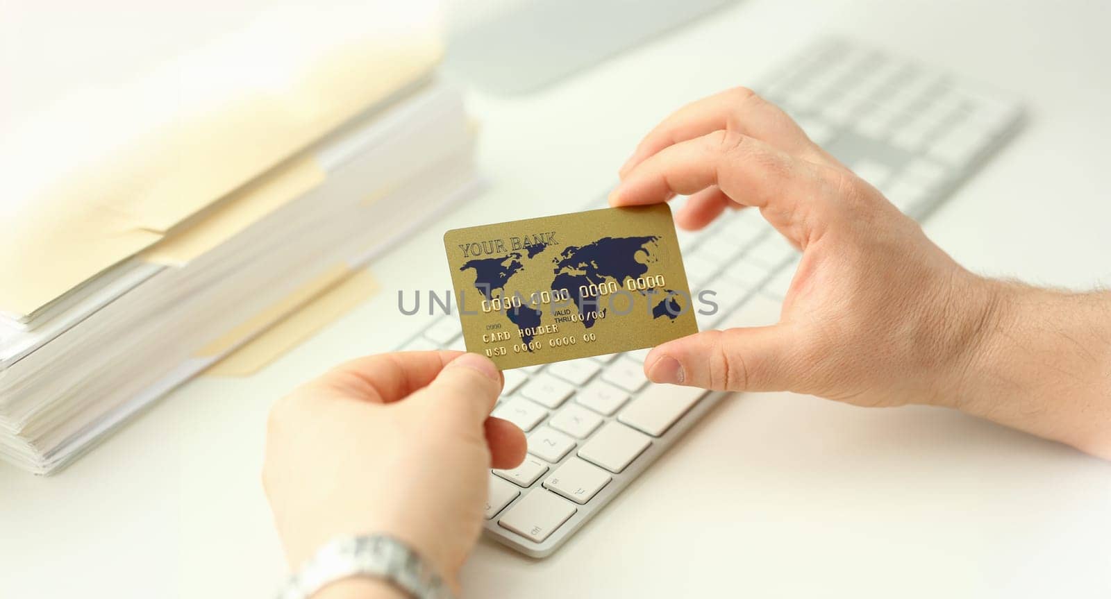 Male hand hold plastic bank card aganist keyboard background. Fast money transaction concept.