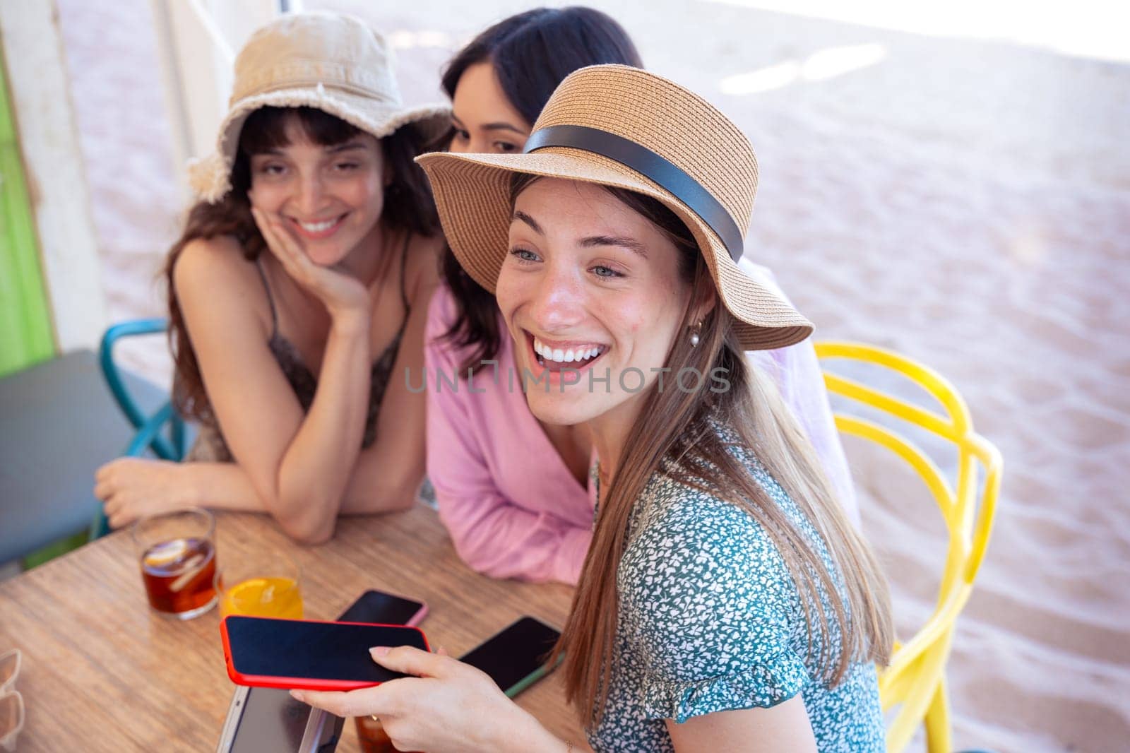 Three happy friends who are in the restaurant with drinks, pay with contactless payment via mobile phone app