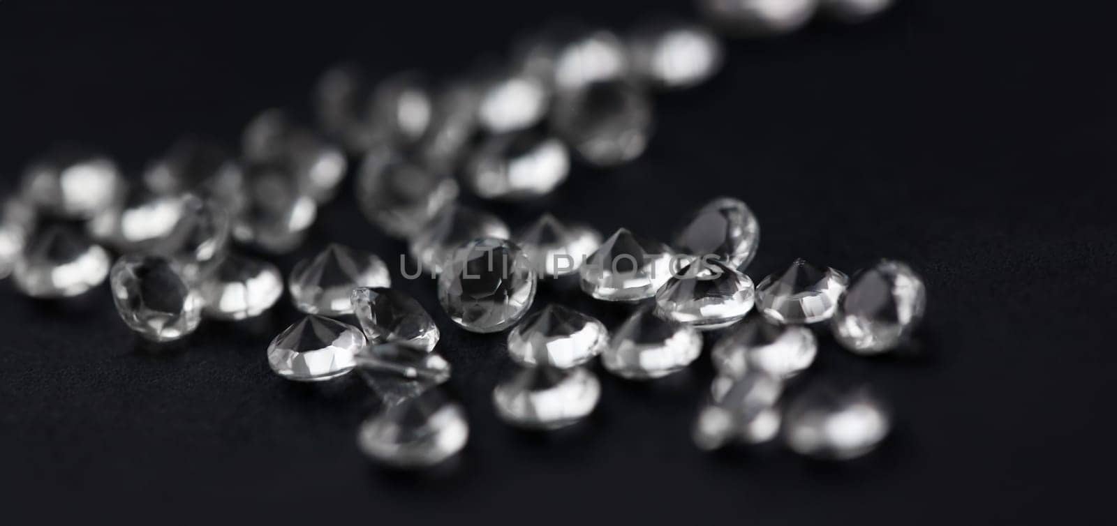 Scattering of white star diamonds on black background table jeweler concept