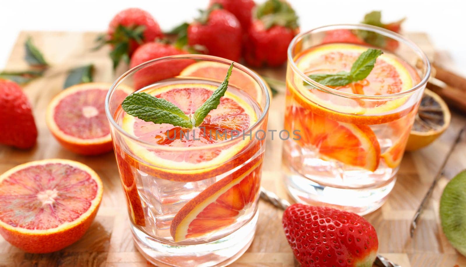 Red orange punch with green mint home made cocktail closeup on wood background
