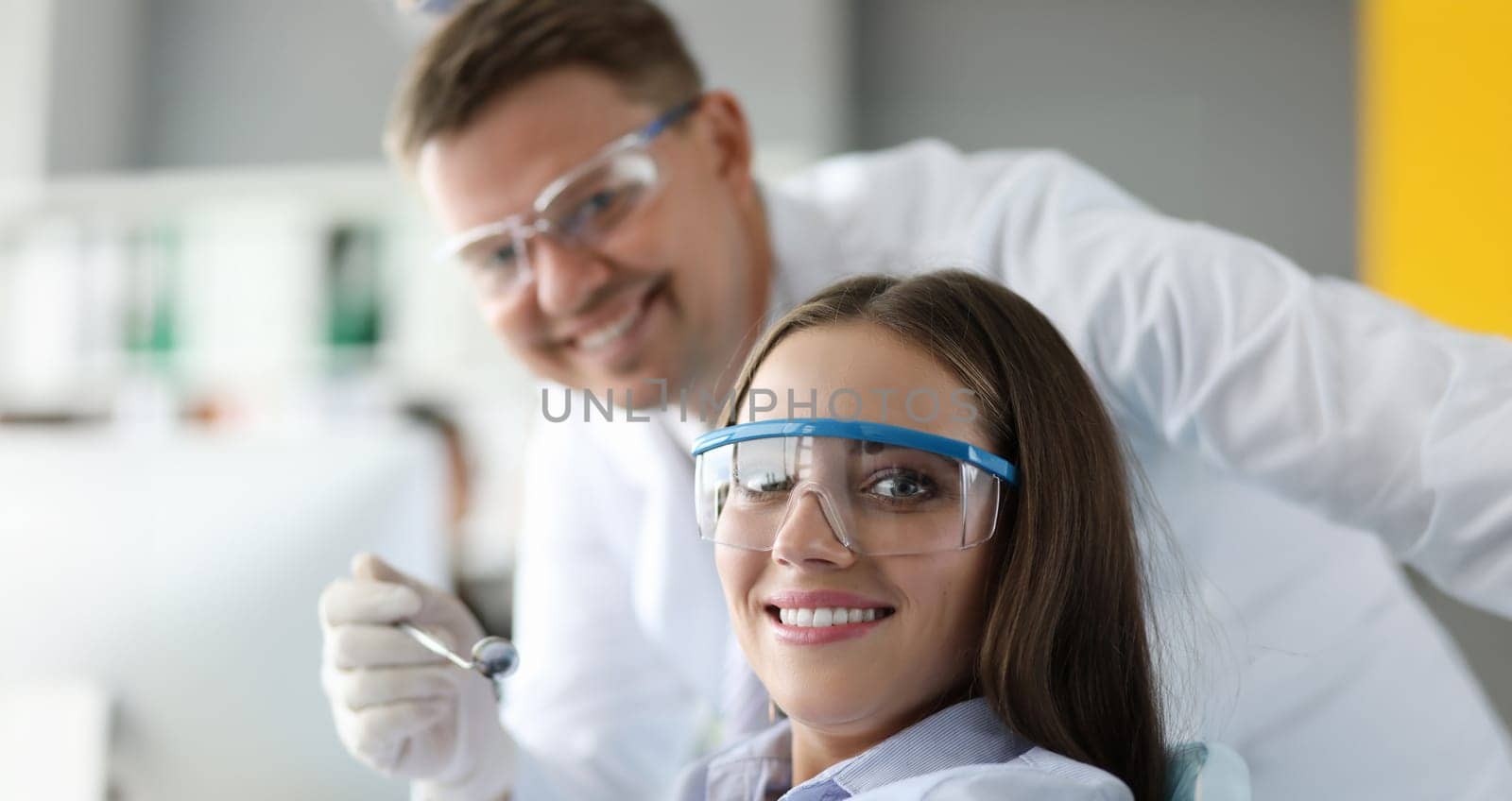 Portrait of beautiful female looking at camera with gladness and smile. Stomatologist examining teeth condition with special tools. Healthcare and dentist concept