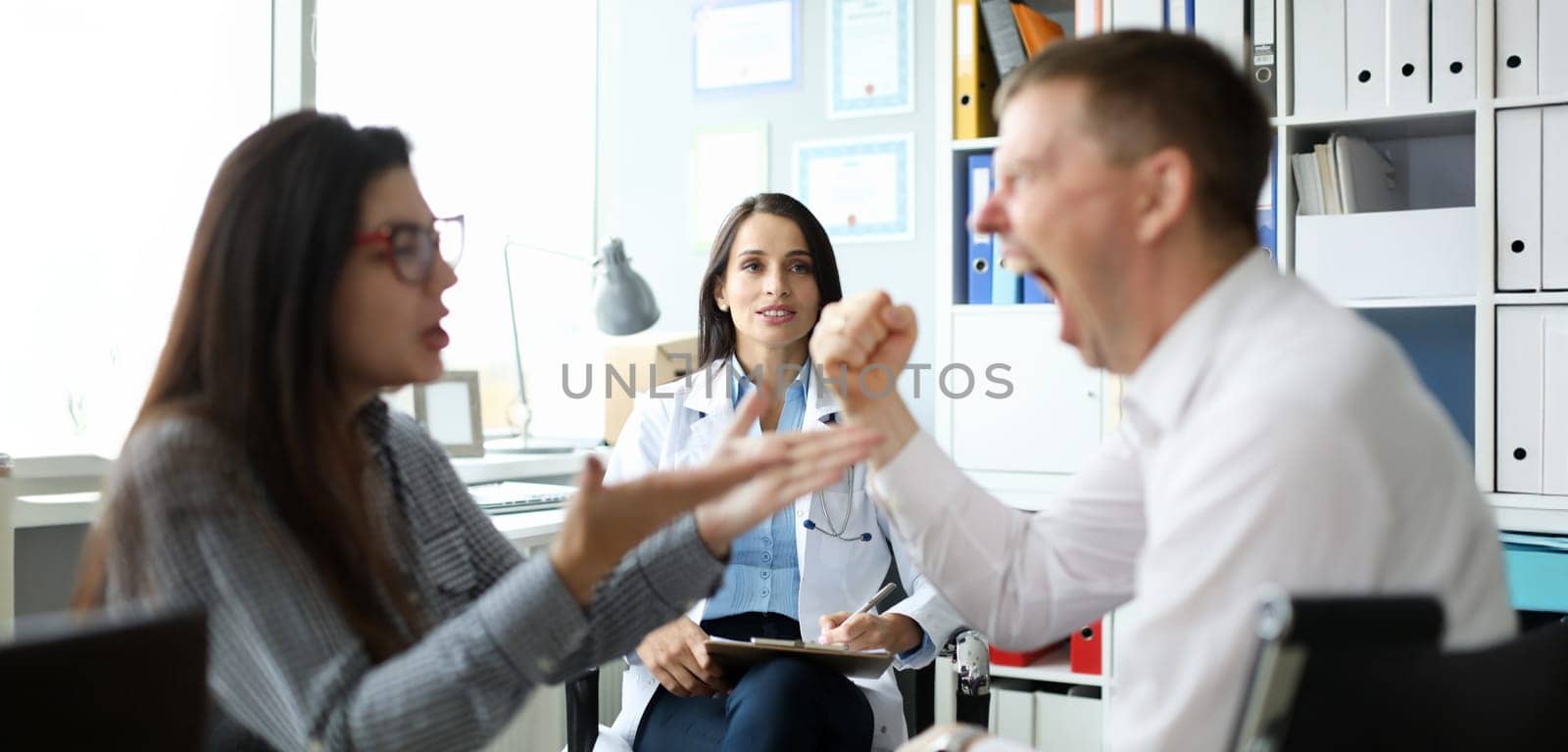 Portrait of cheerful specialist looking at visitors. Married couple listening good news. Surprised woman looking at man screaming with joy. Family planning center concept
