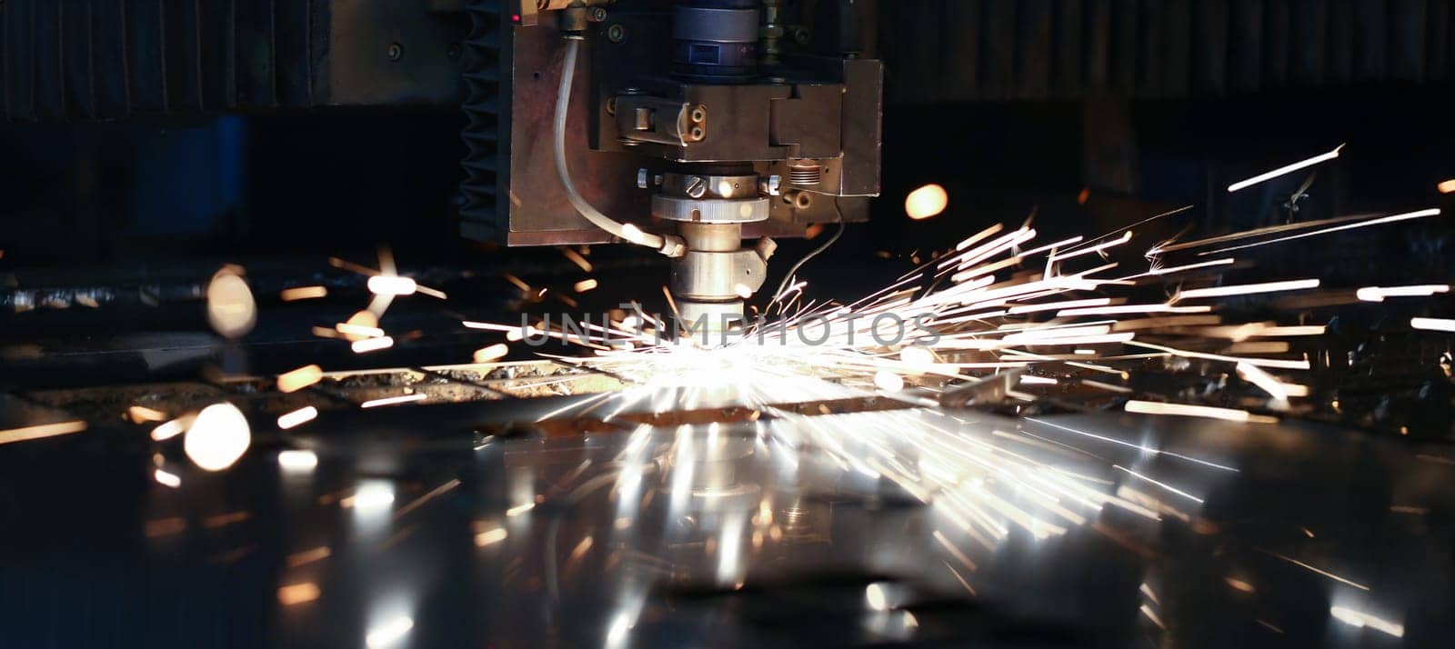 Sparks fly out machine head for metal processing laser metal on metallurgical plant background. Manufacturing finished parts for automotive production concept