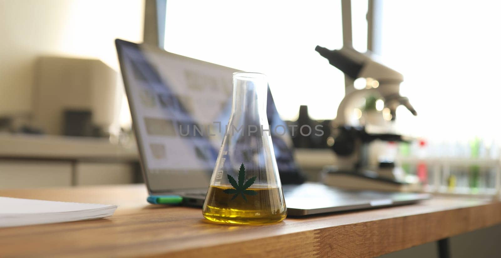 Test tube with yellow cbd oil on natural wooden table chemisrtry lab research background closeup. Medical marijuana concept