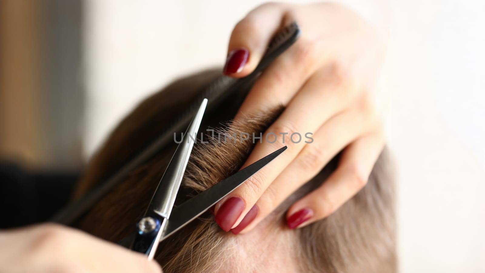 Female hand hold hair scissors aganist hairdresser salon background