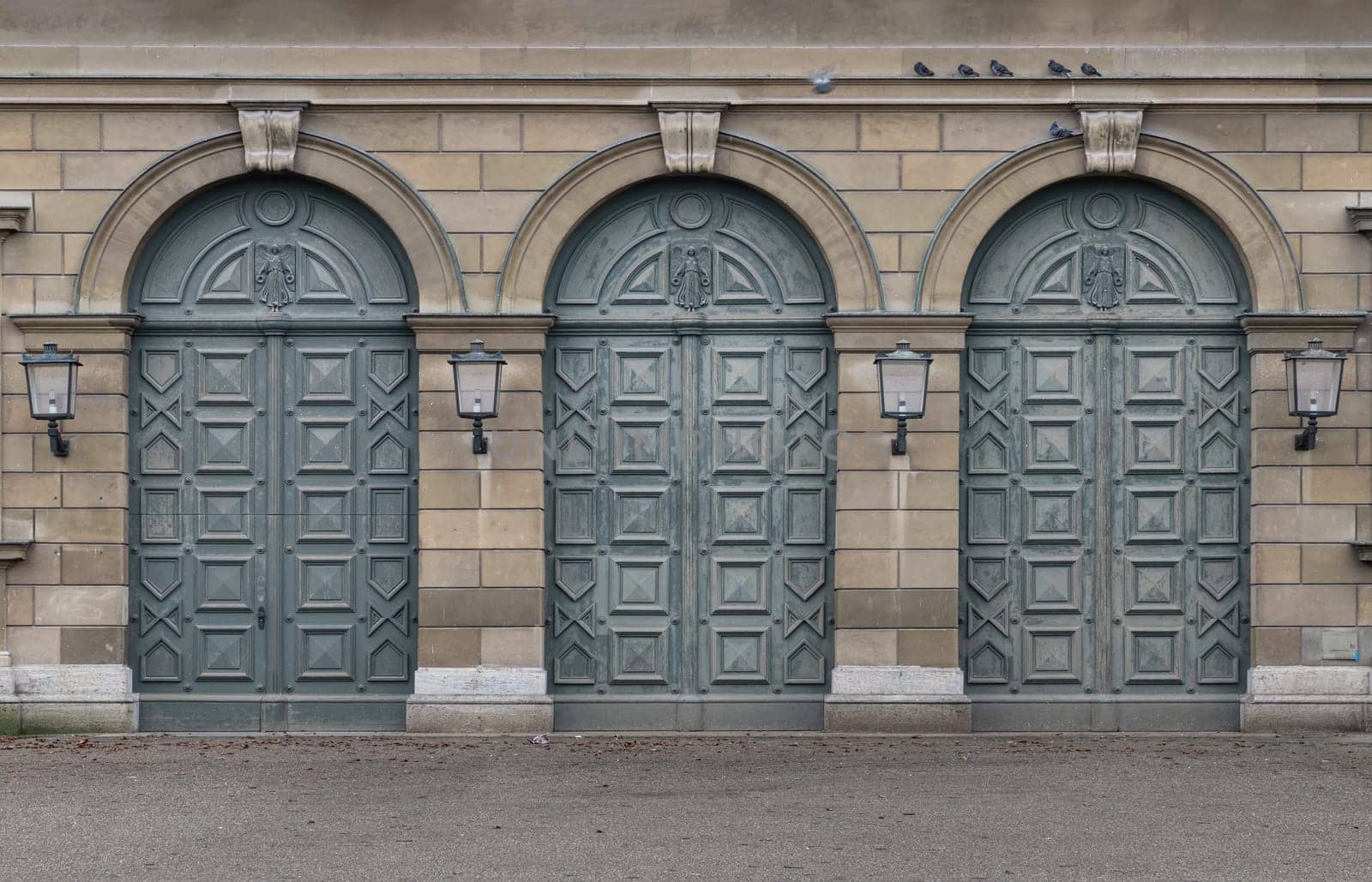 Munich, Germany - Dec 21, 2023 - Facade of arched iron doorway with lamps on stone wall of The Munich Residence Building. Architectural detail of Renaissance baroque style, Space for text, Selective focus.