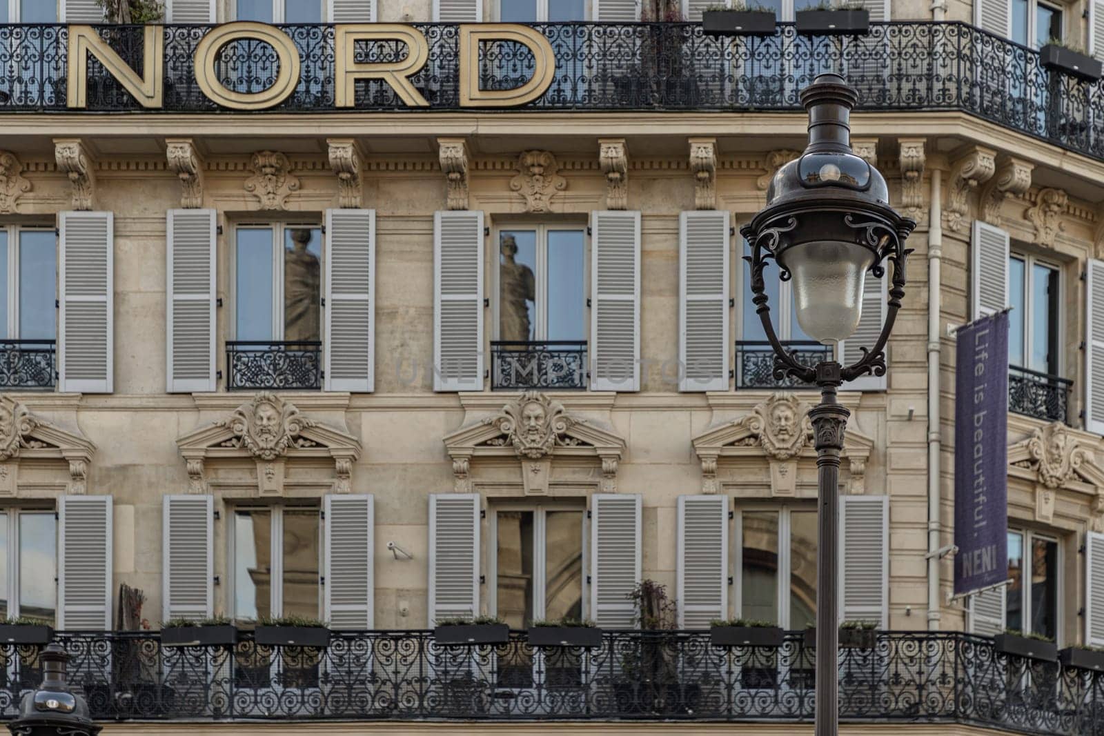 France, Paris - Jan 05, 2024 - Exterior architecture of Traditional French house with typical balconies and windows in Paris. Facade of elegant apartment buildings in the cities of Paris are patterned with french windows and wrought iron black railings, Space for text, Selective focus.
