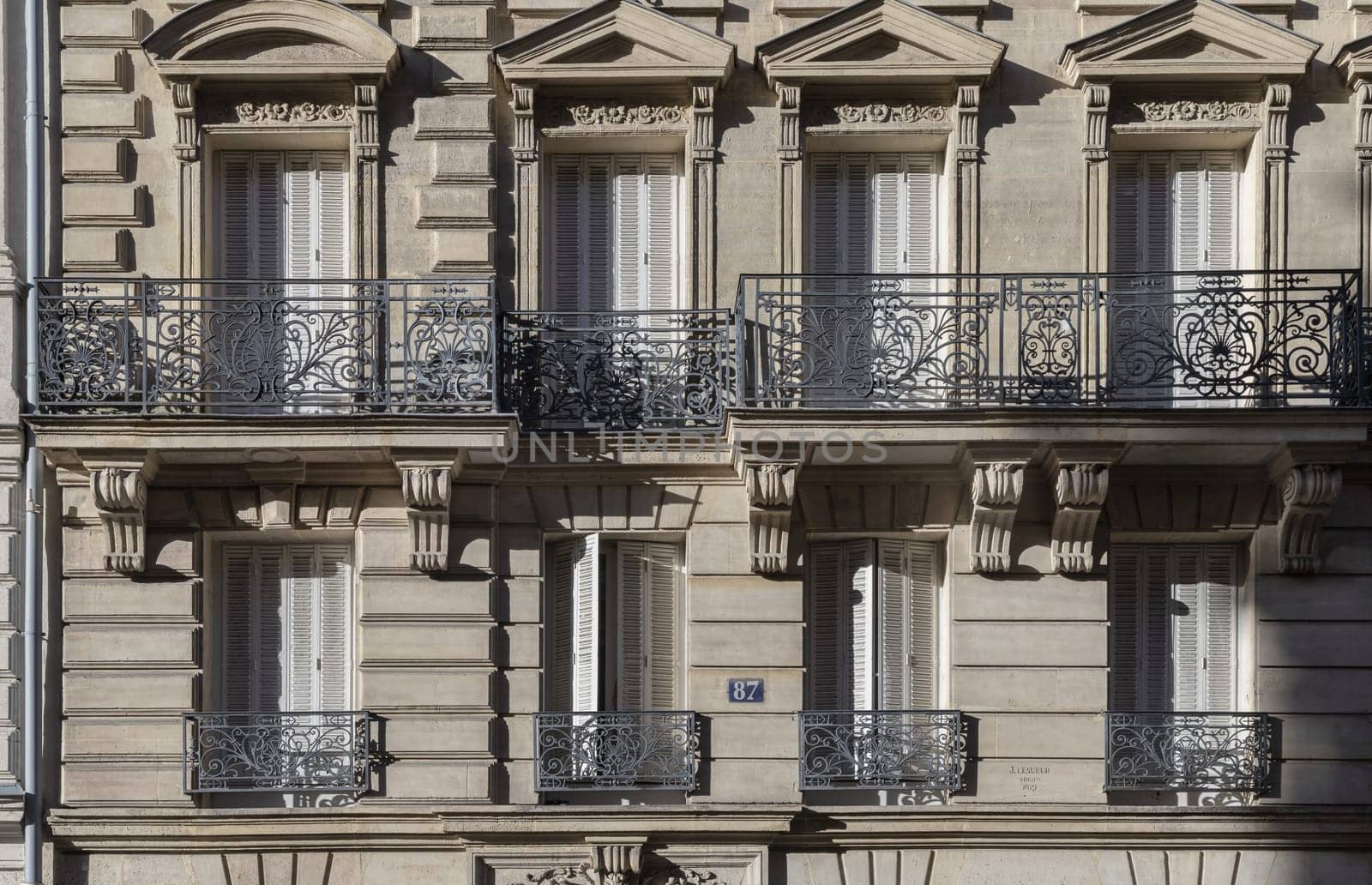 France, Paris - Jan 05, 2024 - Exterior architecture of Traditional French house with typical balconies and windows in Paris. Facade of elegant apartment buildings in the cities of Paris are patterned with french windows and wrought iron black railings, Space for text, Selective focus.