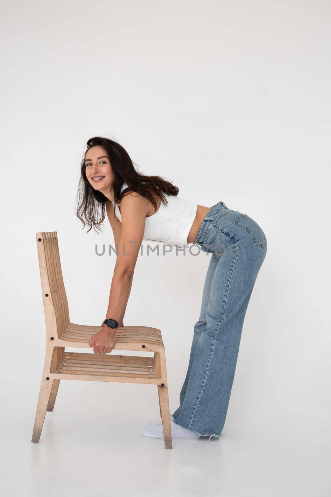 Happy beautiful girl posing in a new hot summer look. Wearing blue jeans and white waistcoat.