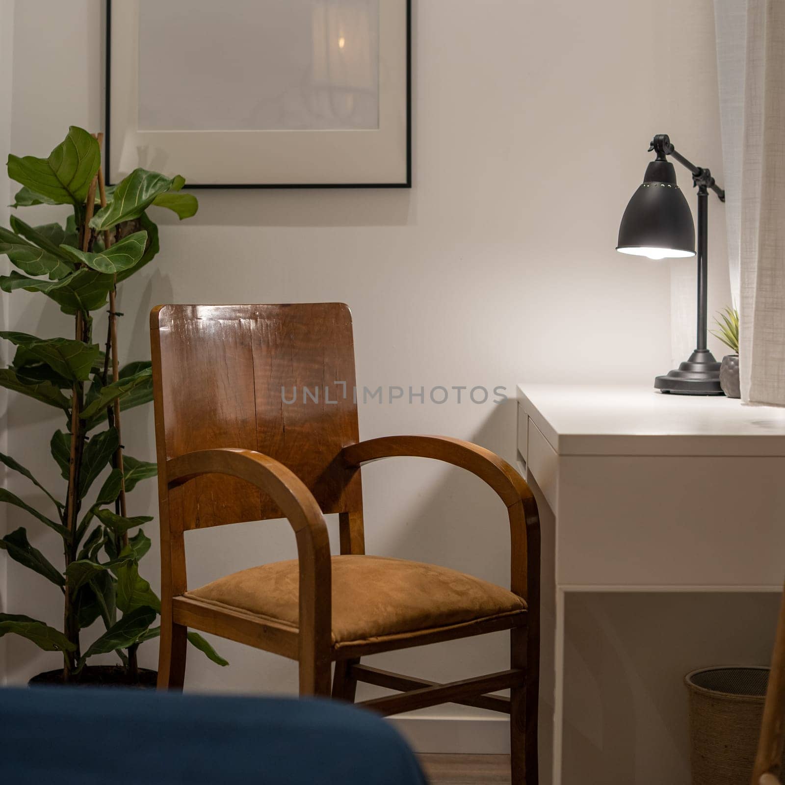 A cozy home office corner featuring a wooden chair, desk, lamp, and plant, creating a warm and inviting workspace ambiance.