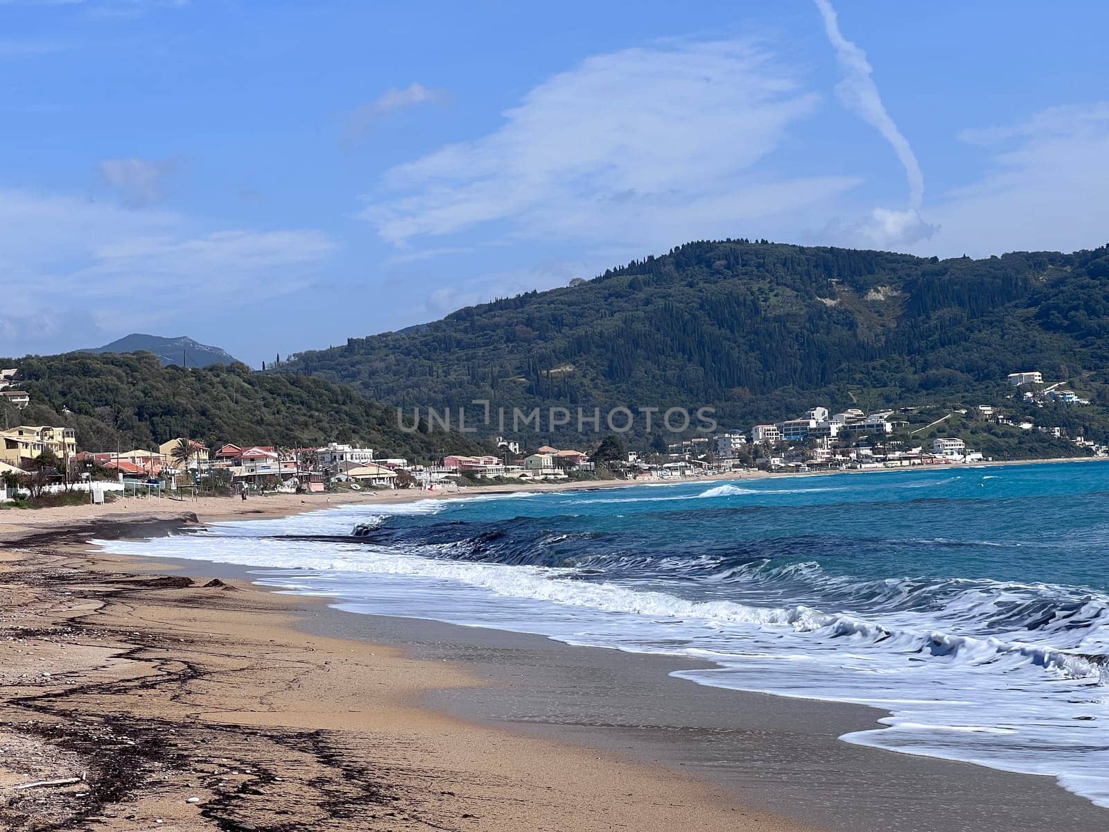 A beautiful landscape of the coast of the island of Corfu in the Ionian Sea of the Mediterranean in Greece. Pure blue clear water washes over the shores of the Greek island. High quality photo