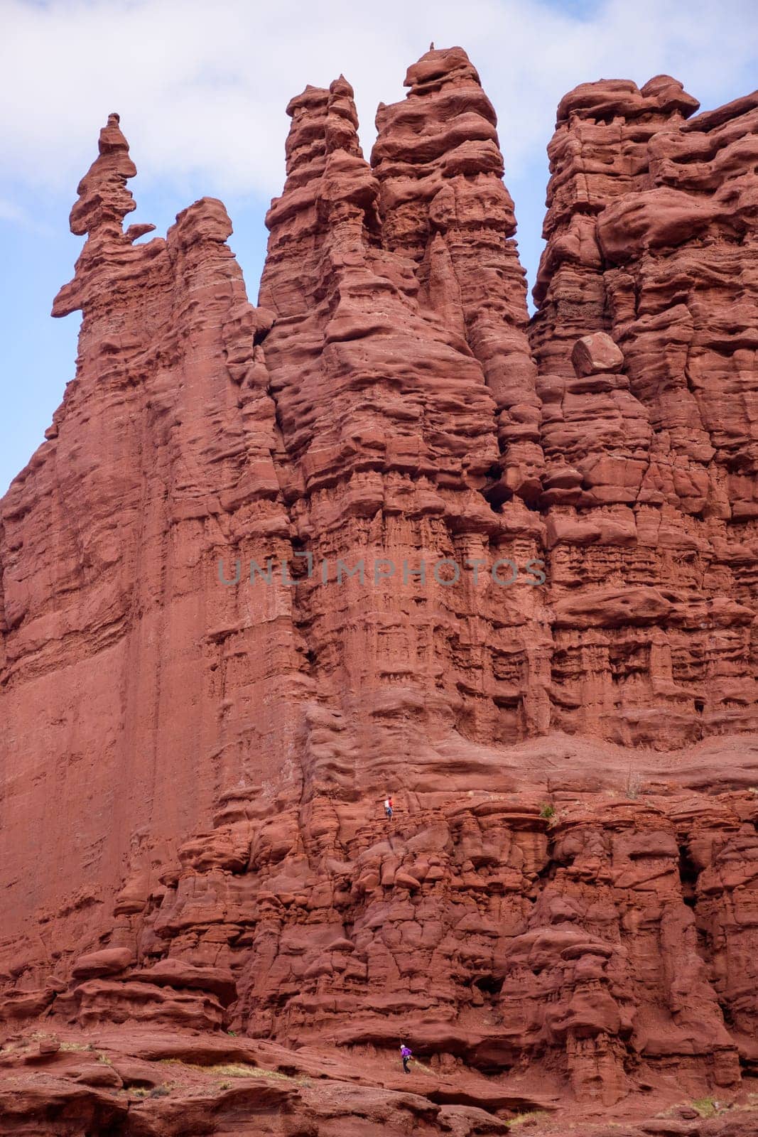 Two rock climbers ascend the red rock formations of Fisher Towers in Moab, Utah. The dramatic landscape and tall spires create a sense of adventure in this popular rock climbing destination - USA