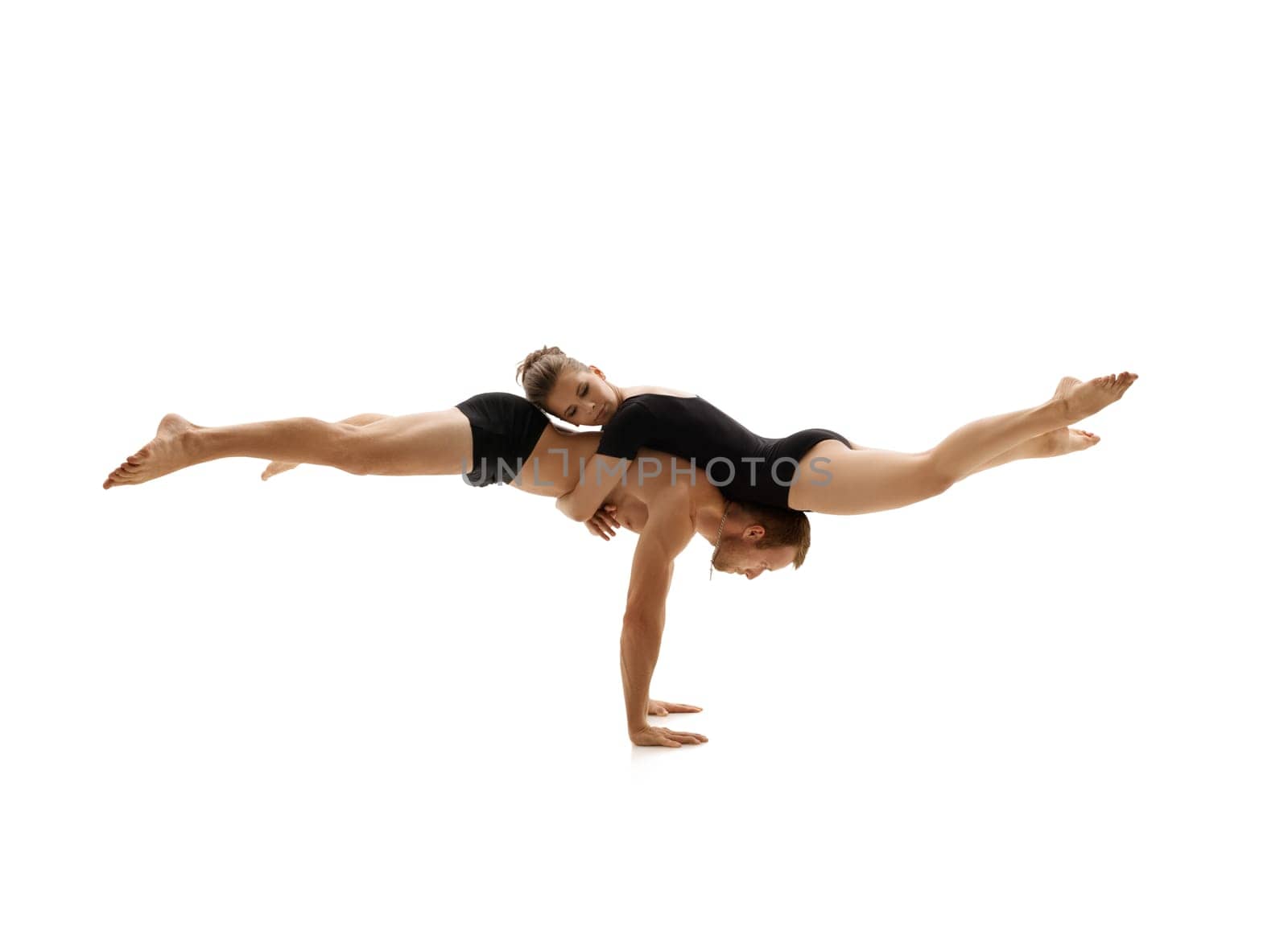 Young couple dressed in sports clothes doing acrobatics together in studio