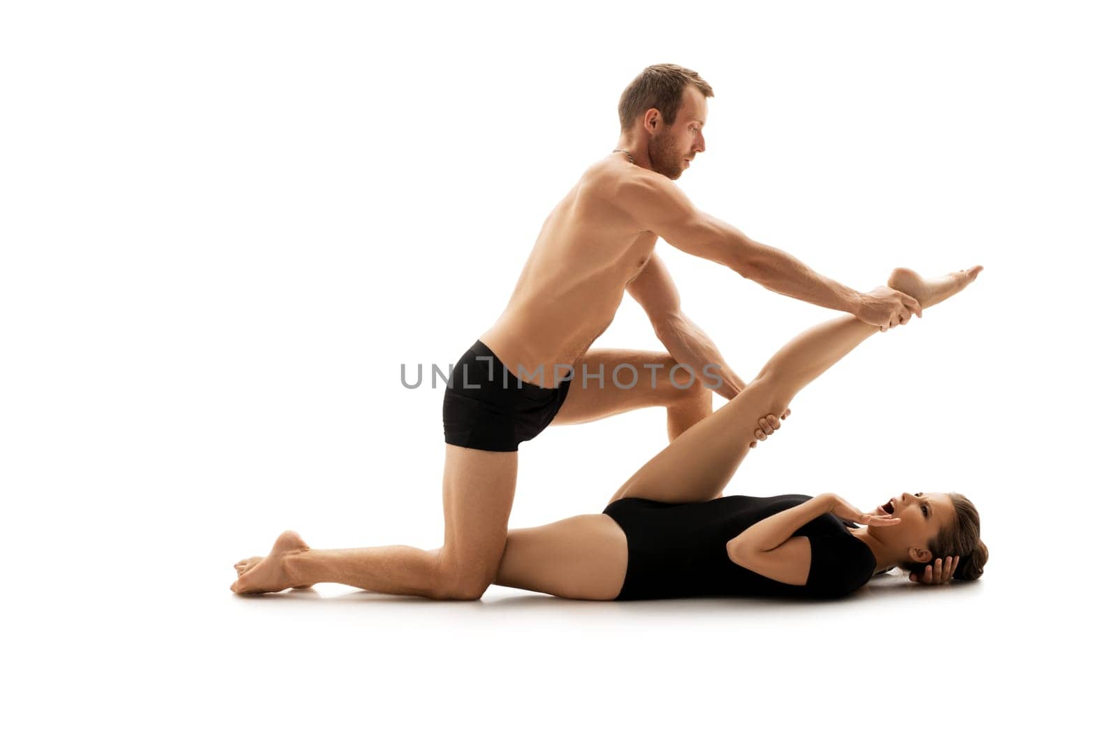 Young couple dressed in sports clothes doing acrobatics together in studio