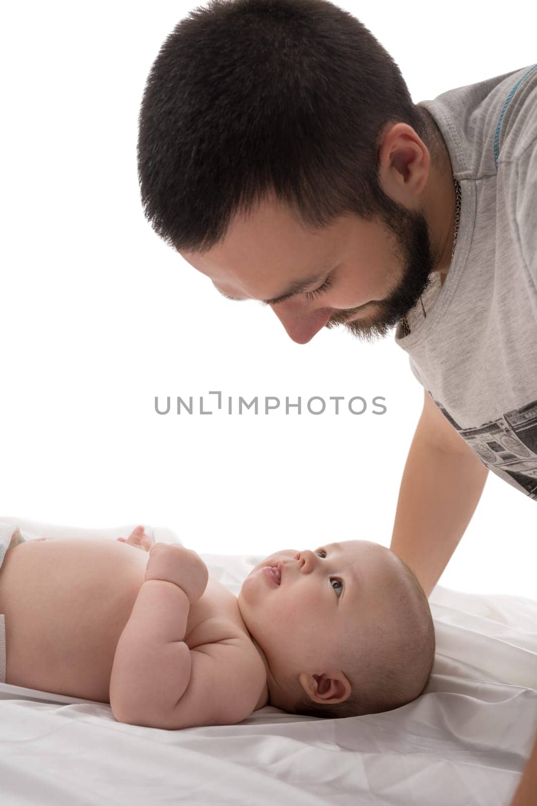 Bearded young dad with newborn looking at him affectionately studio shot