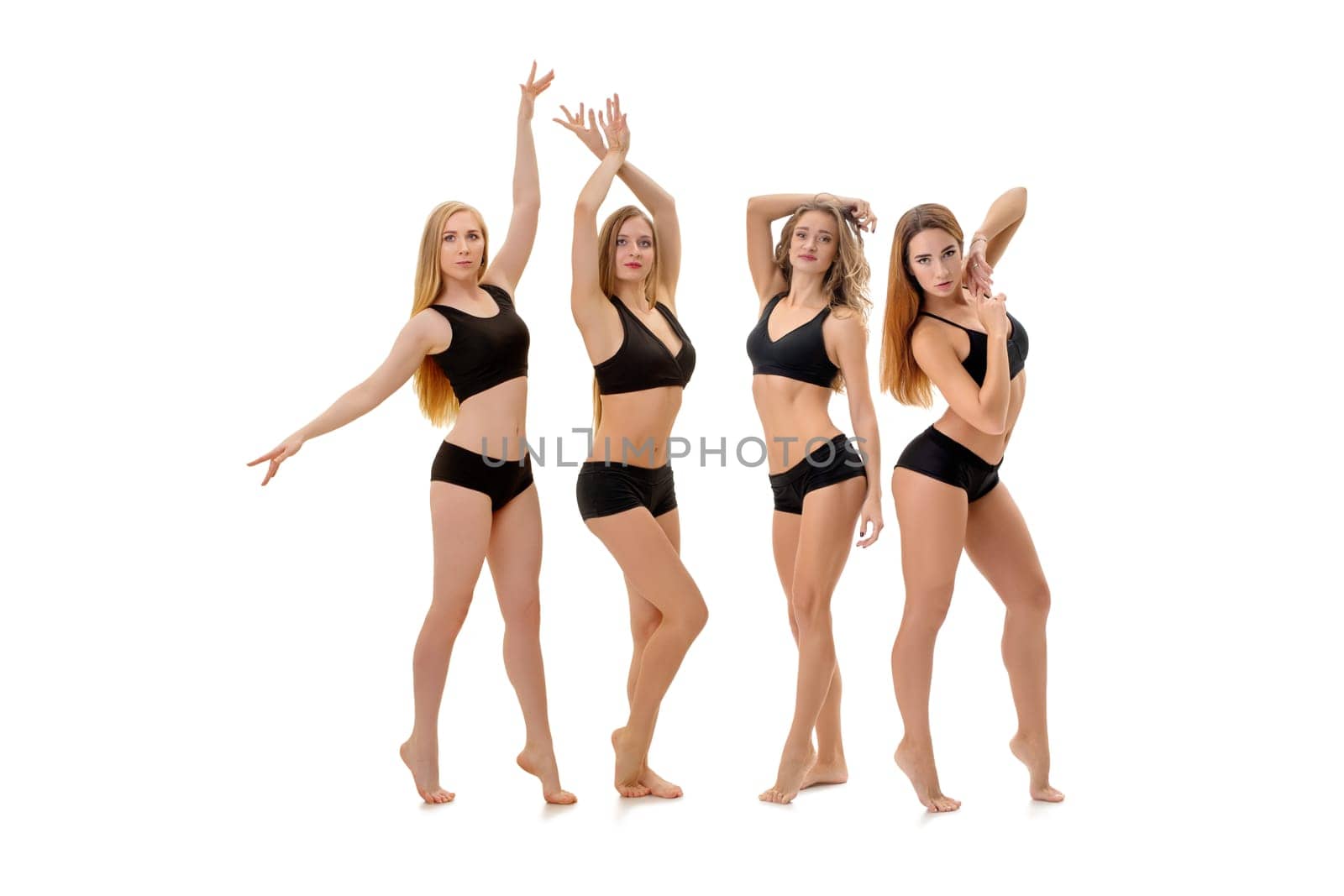 Graceful pretty fitness trainers in black tops and pants posing in studio