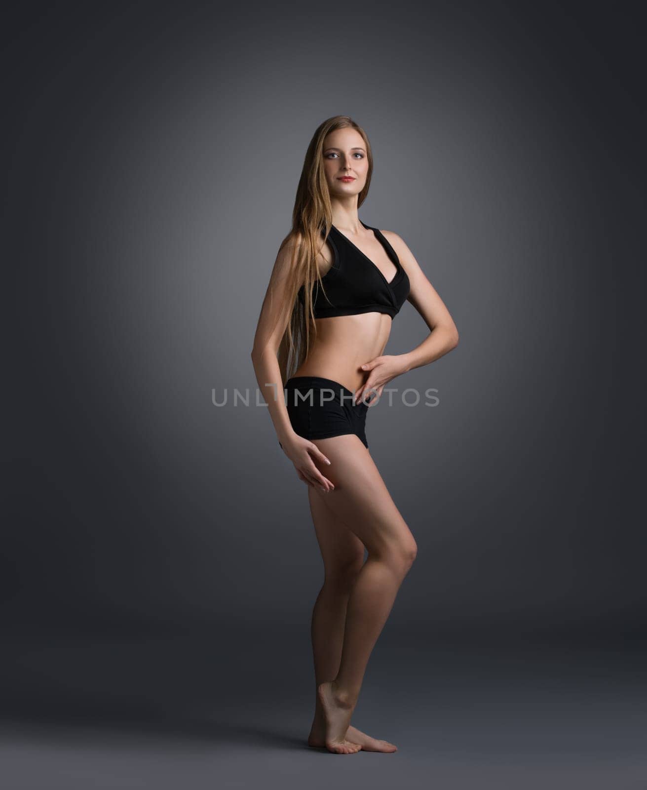 Pretty sportswoman in black top and shorts posing in studio