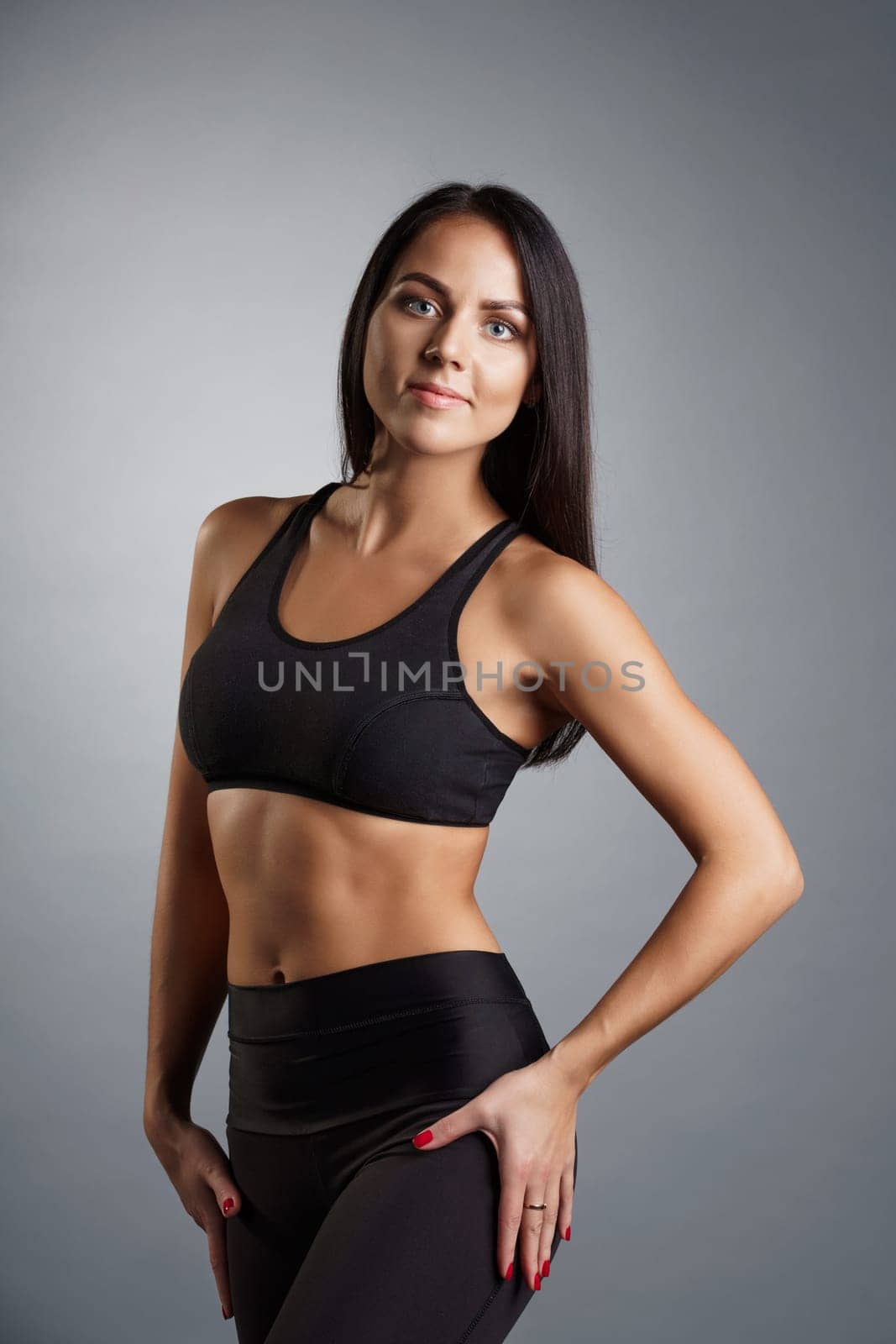 Pretty young fitness trainer in black top and leggings studio portrait