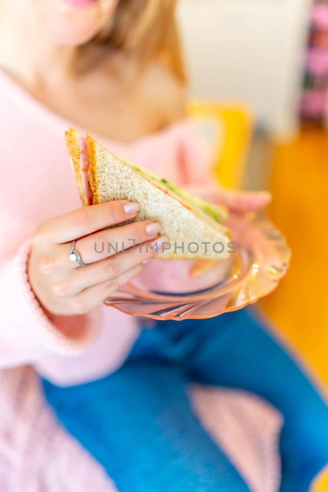 Vertical close-up of the hand of a cauacsian adult, woman holding a homemade sandwich ready to eat