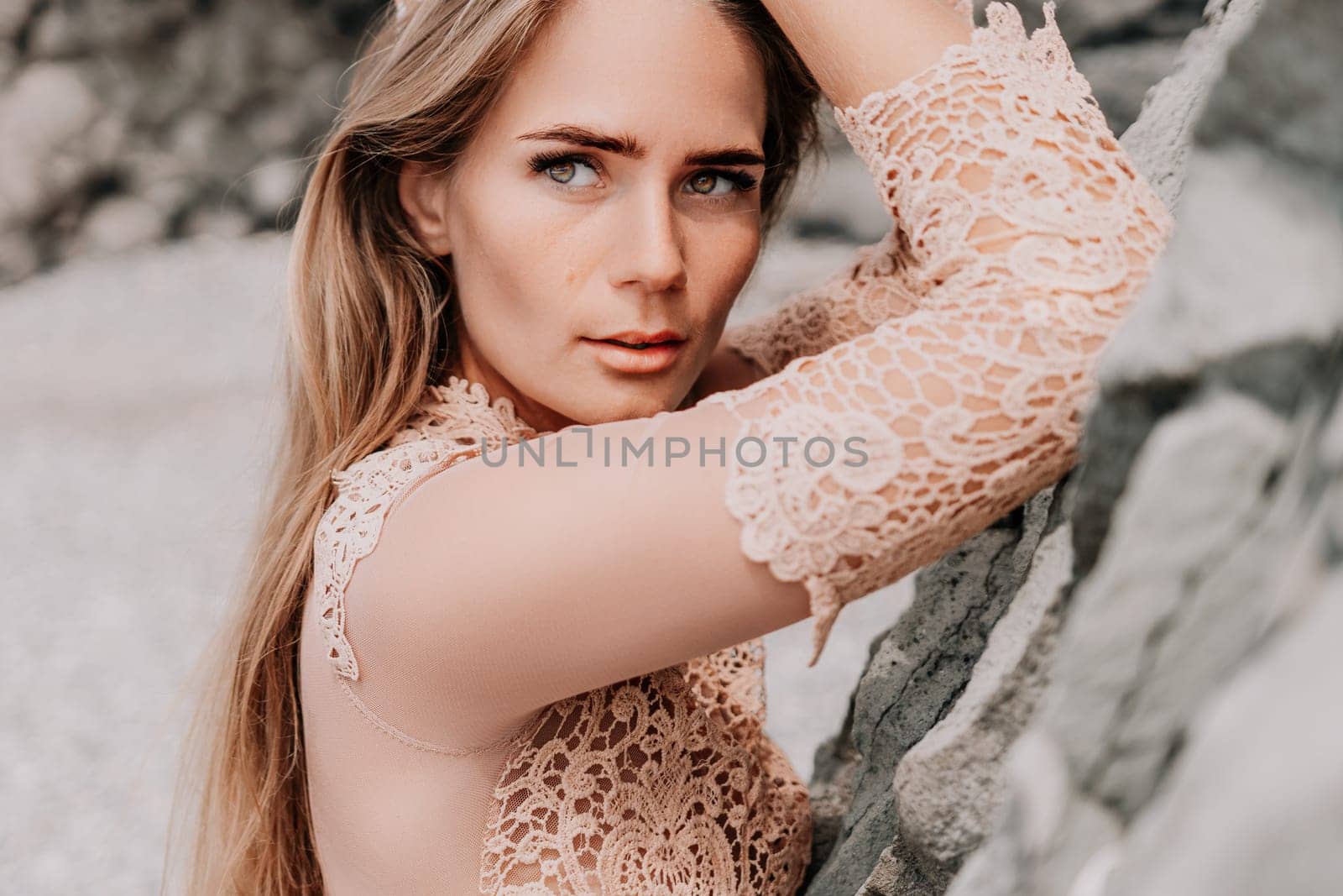 Woman summer travel sea. Happy tourist in beige dress enjoy taking picture outdoors for memories. Woman traveler posing on the beach surrounded by volcanic mountains, sharing travel adventure journey by panophotograph