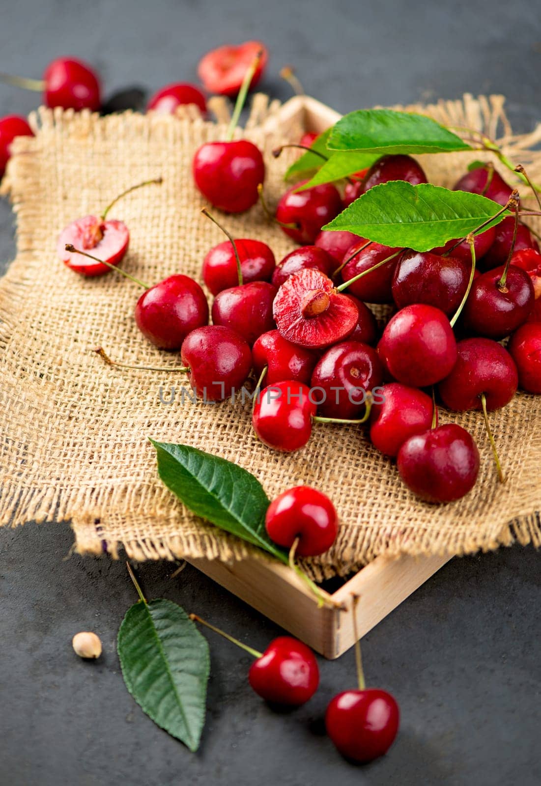 Cherry summer background. A large number of cherries with leaves on the table, on a black background. close-up. by aprilphoto