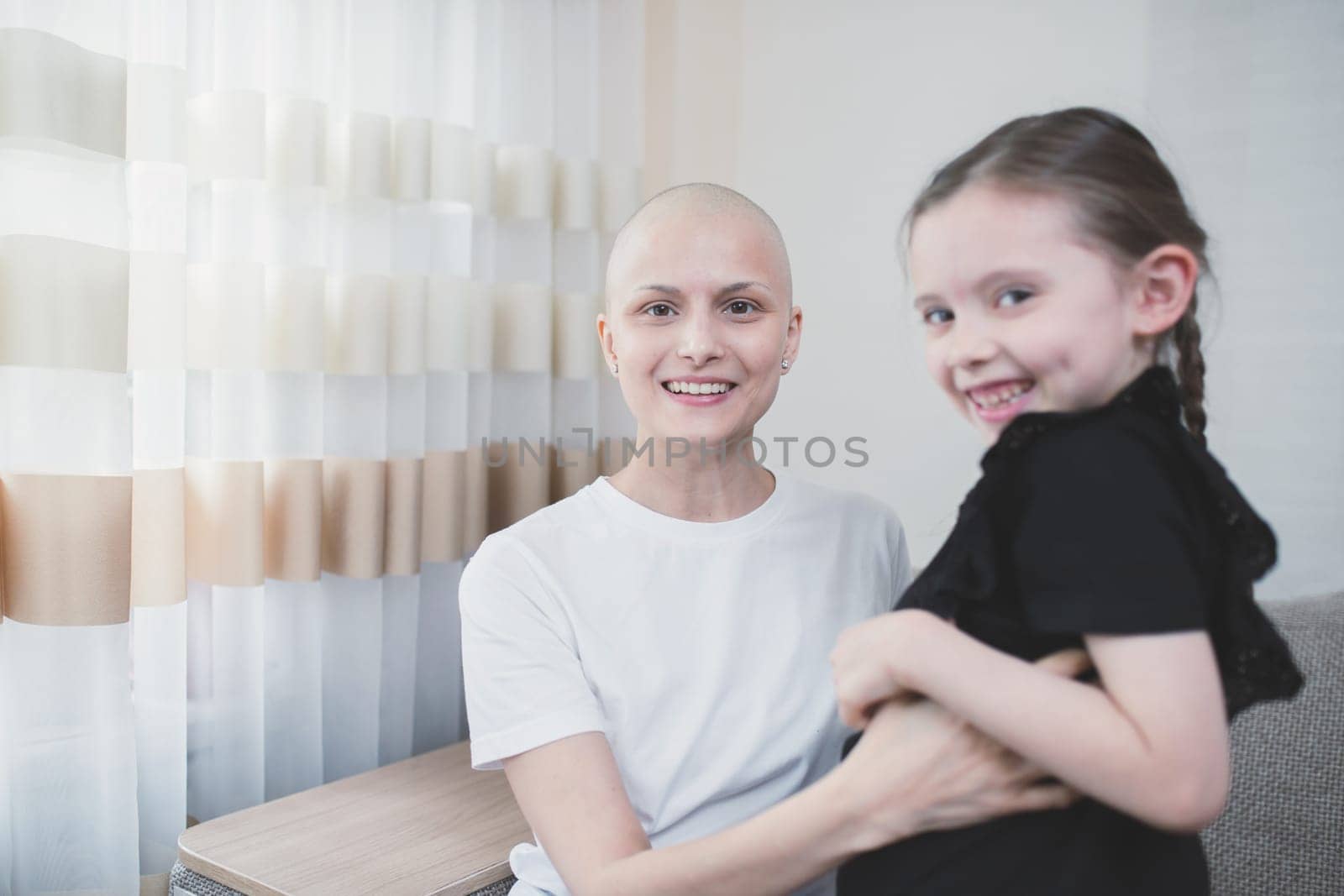 Happy bald woman with alopecia smiling and joyful spending time with her daughter.
