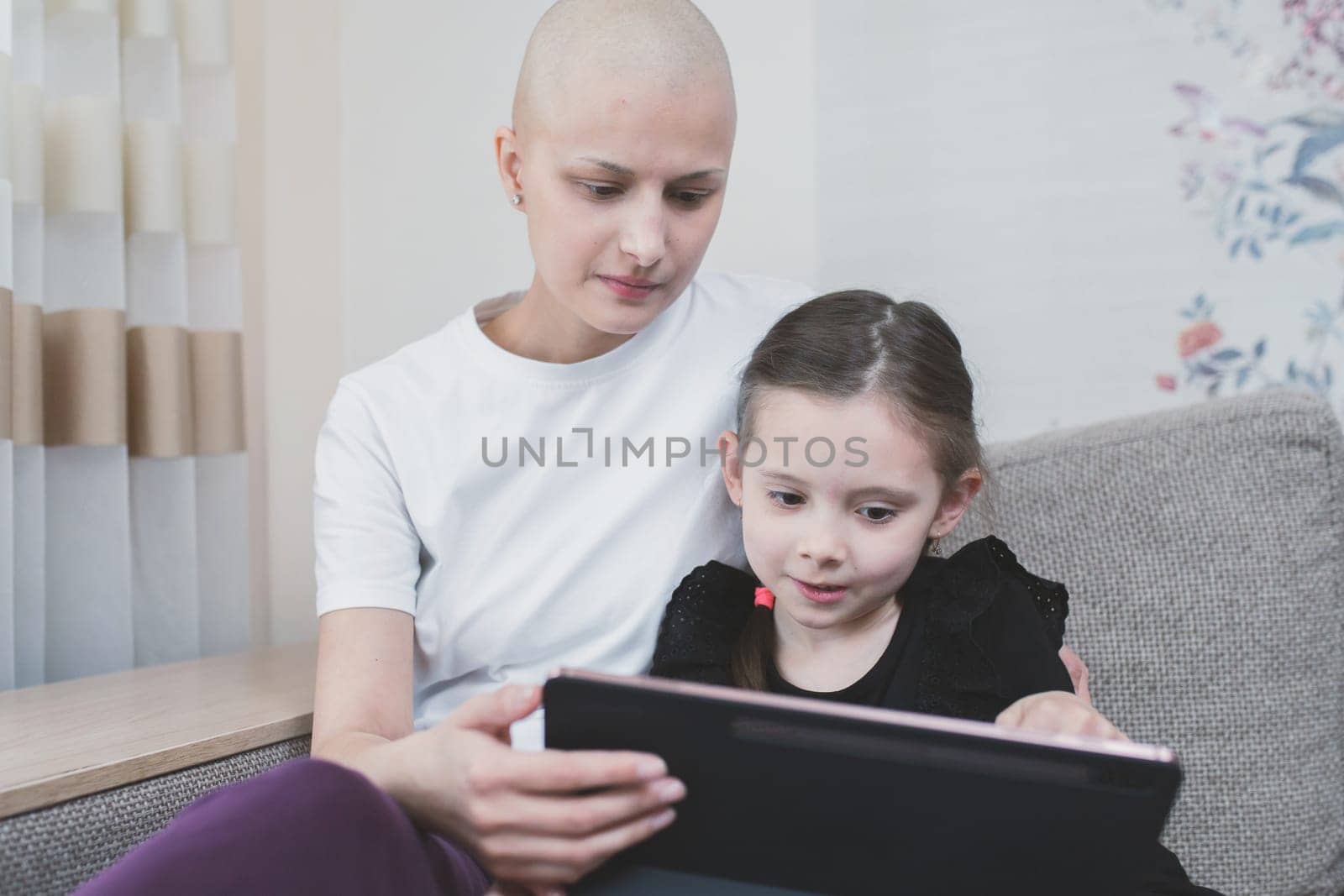 Kid girl spend time with his mother with a diagnosis of leukemia at home. Family support concept.