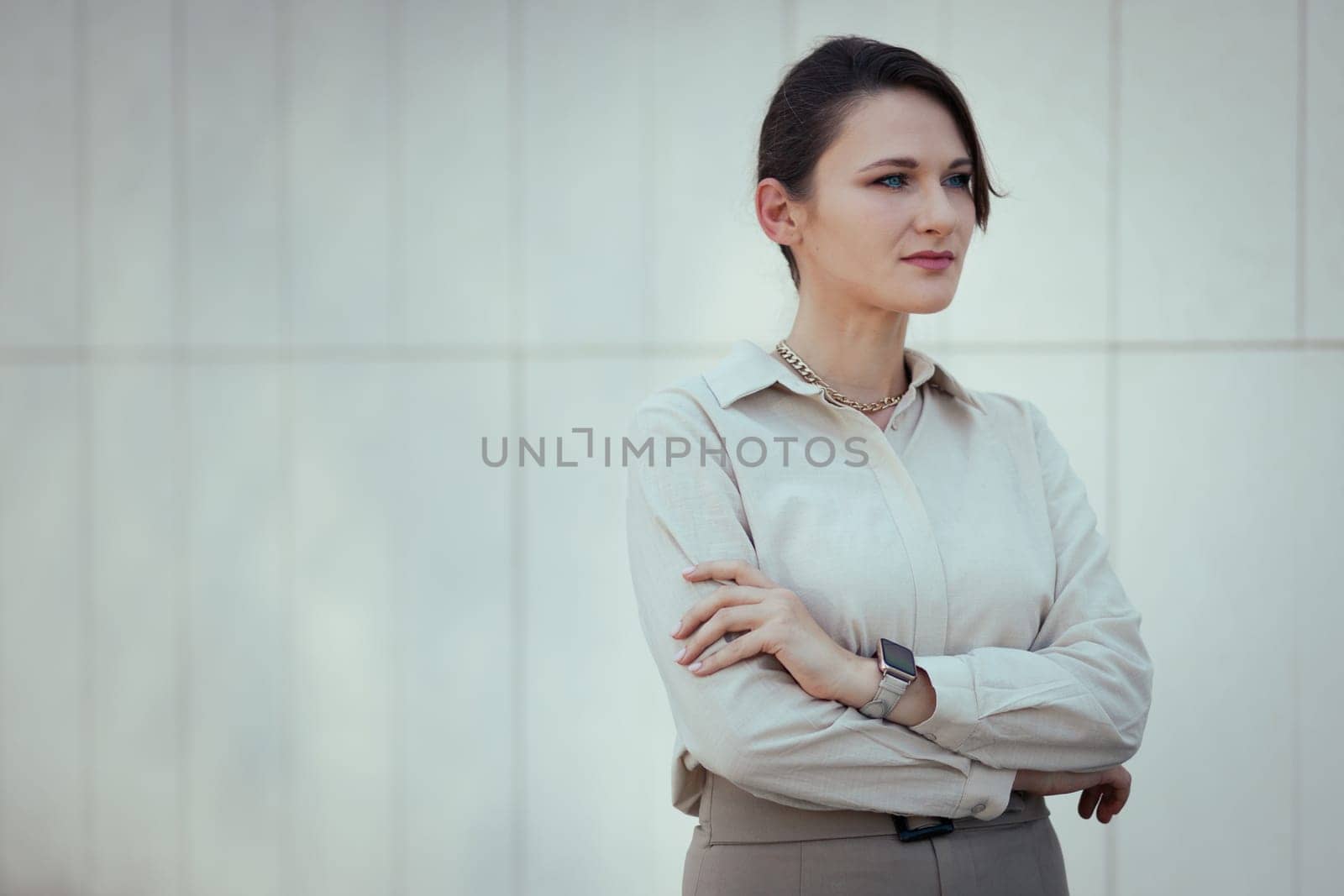 Caucasian woman in office or business style in clothes. Restrained female image in beige tones with a smart watch, copy space