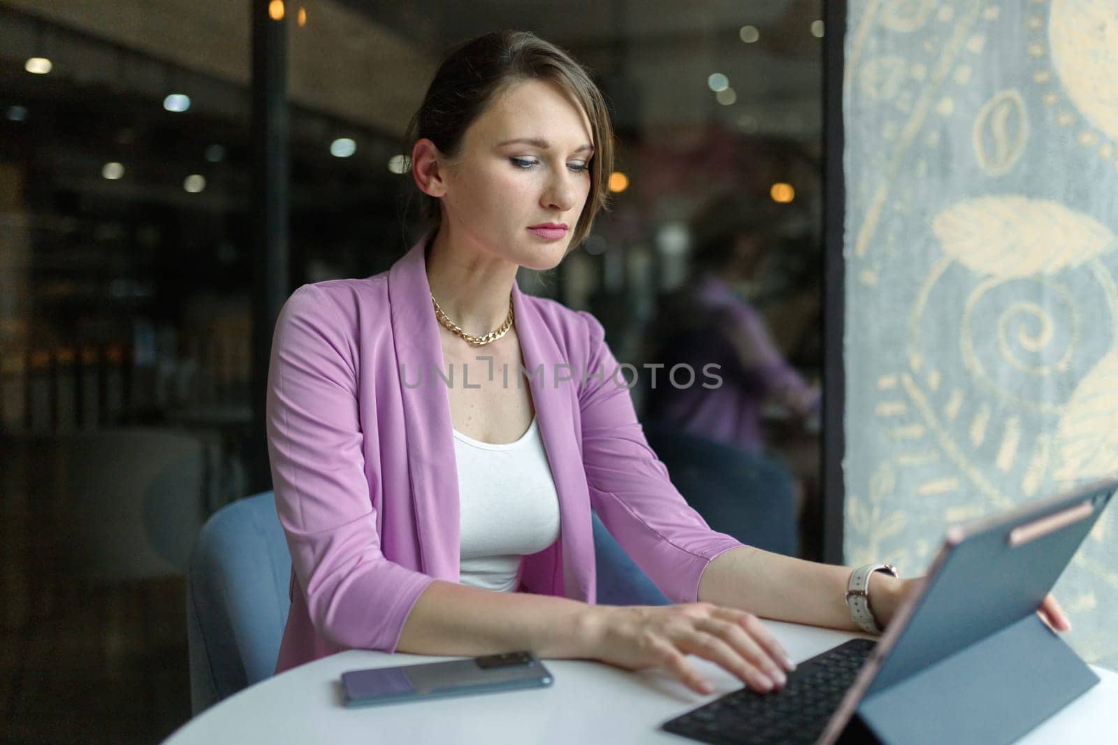 Portrait of a young beautiful business woman sitting in cafe with a laptop. Remote work in a coffee shop.