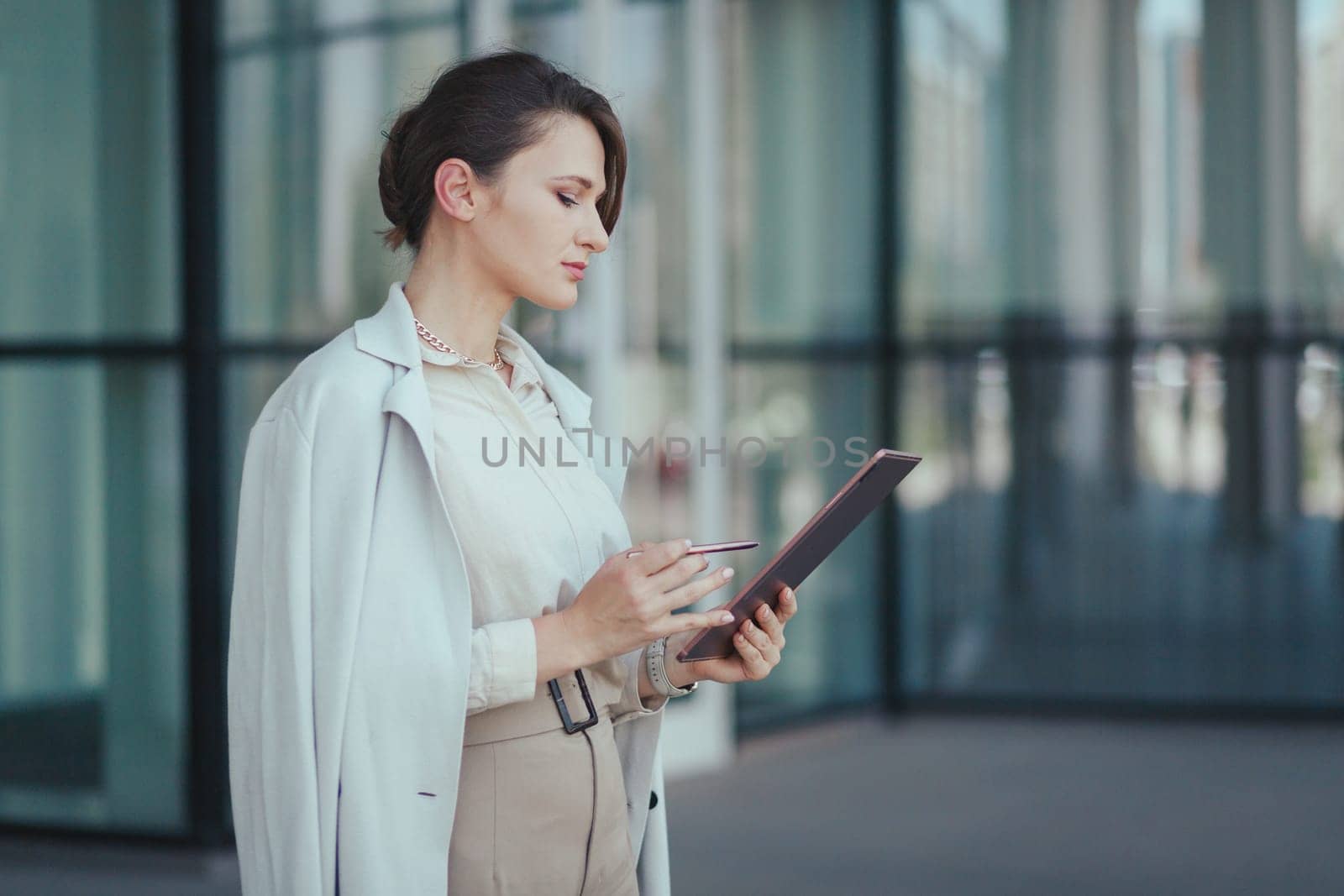Portrait of smart caucasian young entrepreneur fashion woman using her digital tablet while standing in the office building.