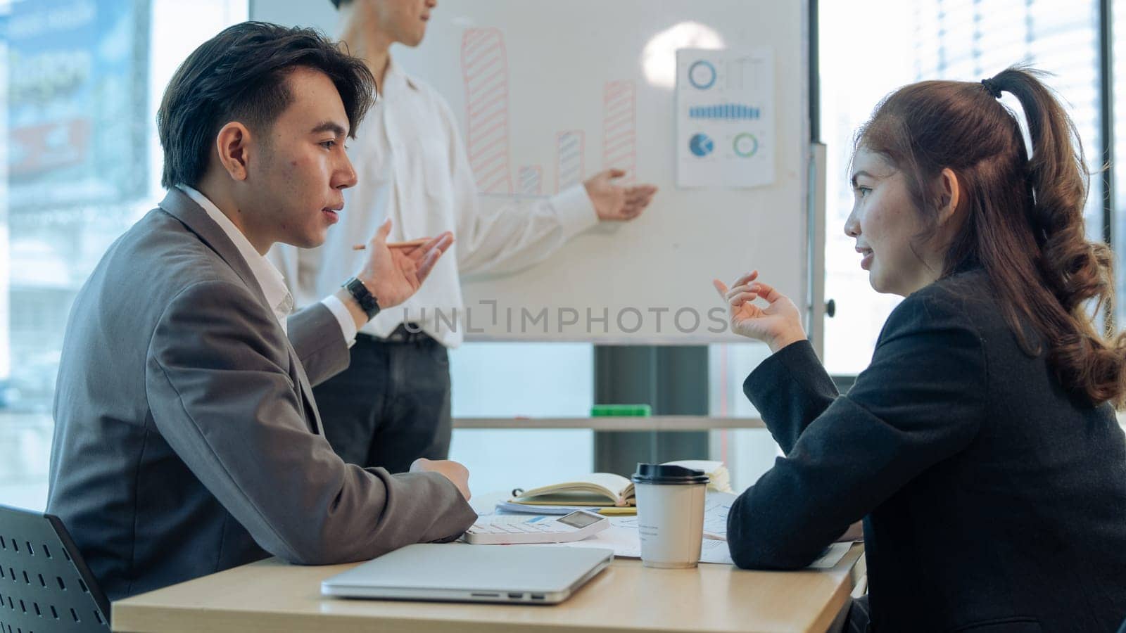 Young Business answering a colleague question during a presentation in boarding room.