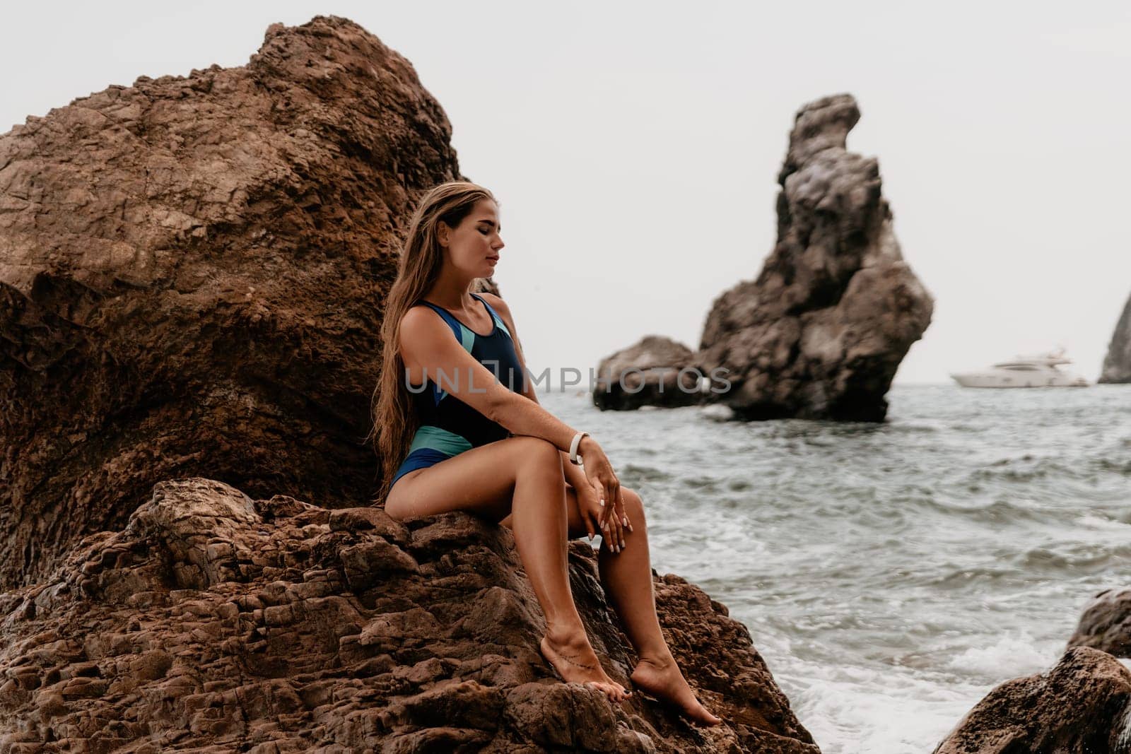 Woman summer travel sea. Happy tourist in blue bikini enjoy taking picture outdoors for memories. Woman traveler posing on the beach surrounded by volcanic mountains, sharing travel adventure journey by panophotograph